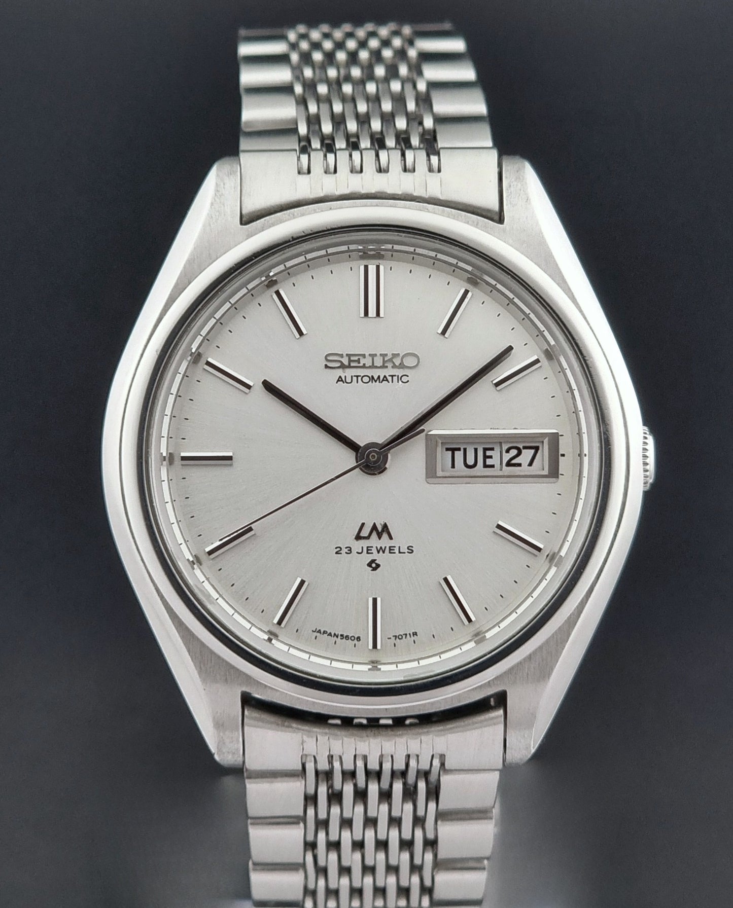 Vintage Seiko Wristwatch 5606-7071  with a metallic band on a dark background close dial view