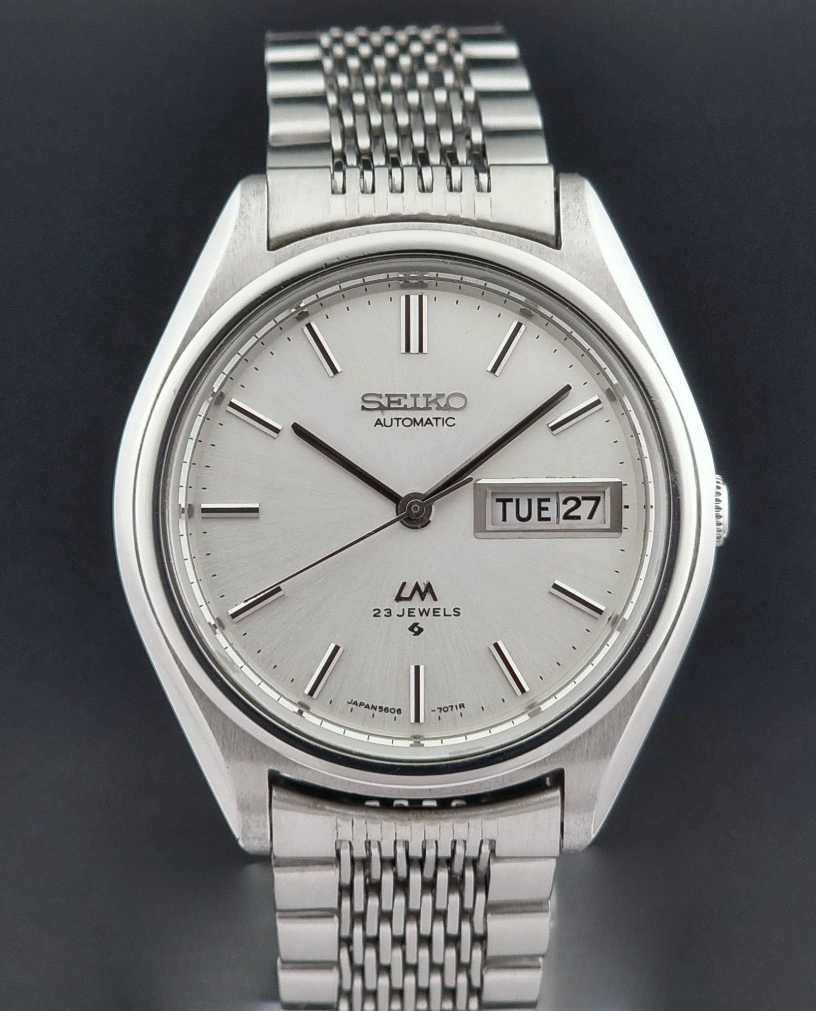 Vintage Seiko Wristwatch 5606-7071  with a metallic band on a dark background close dial view