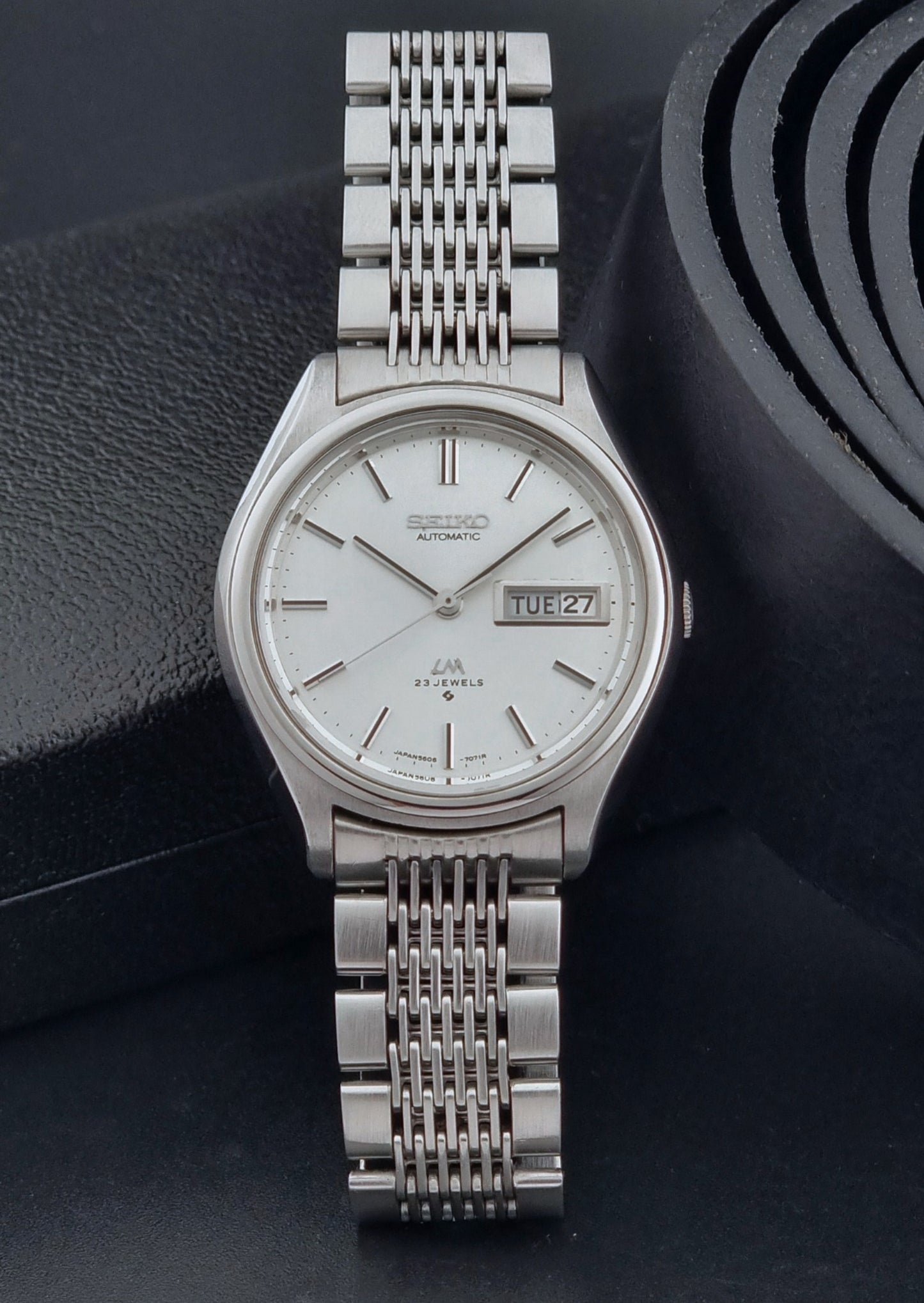 Vintage Seiko Wristwatch 5606-7071  with a metallic band on a dark background dial view