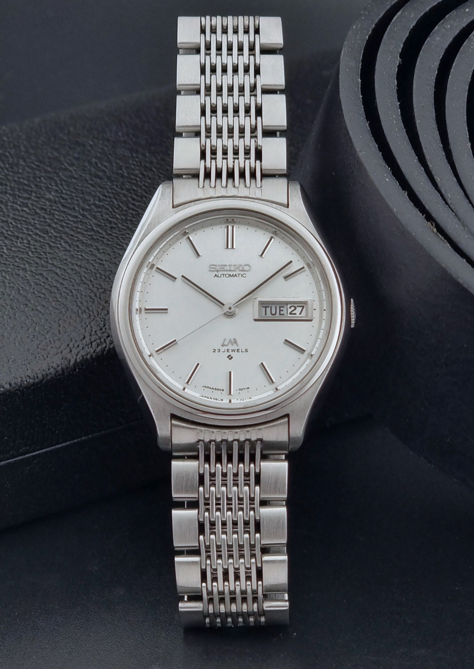 Vintage Seiko Wristwatch 5606-7071  with a metallic band on a dark background dial view