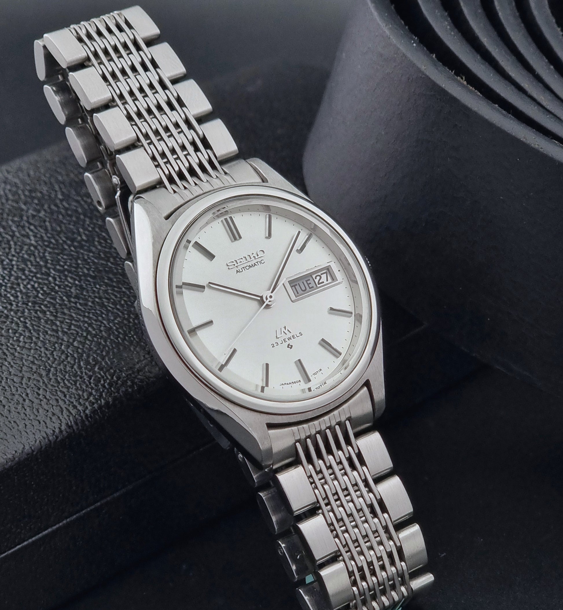 Vintage Seiko Wristwatch 5606-7071  with a metallic band on a dark background side view