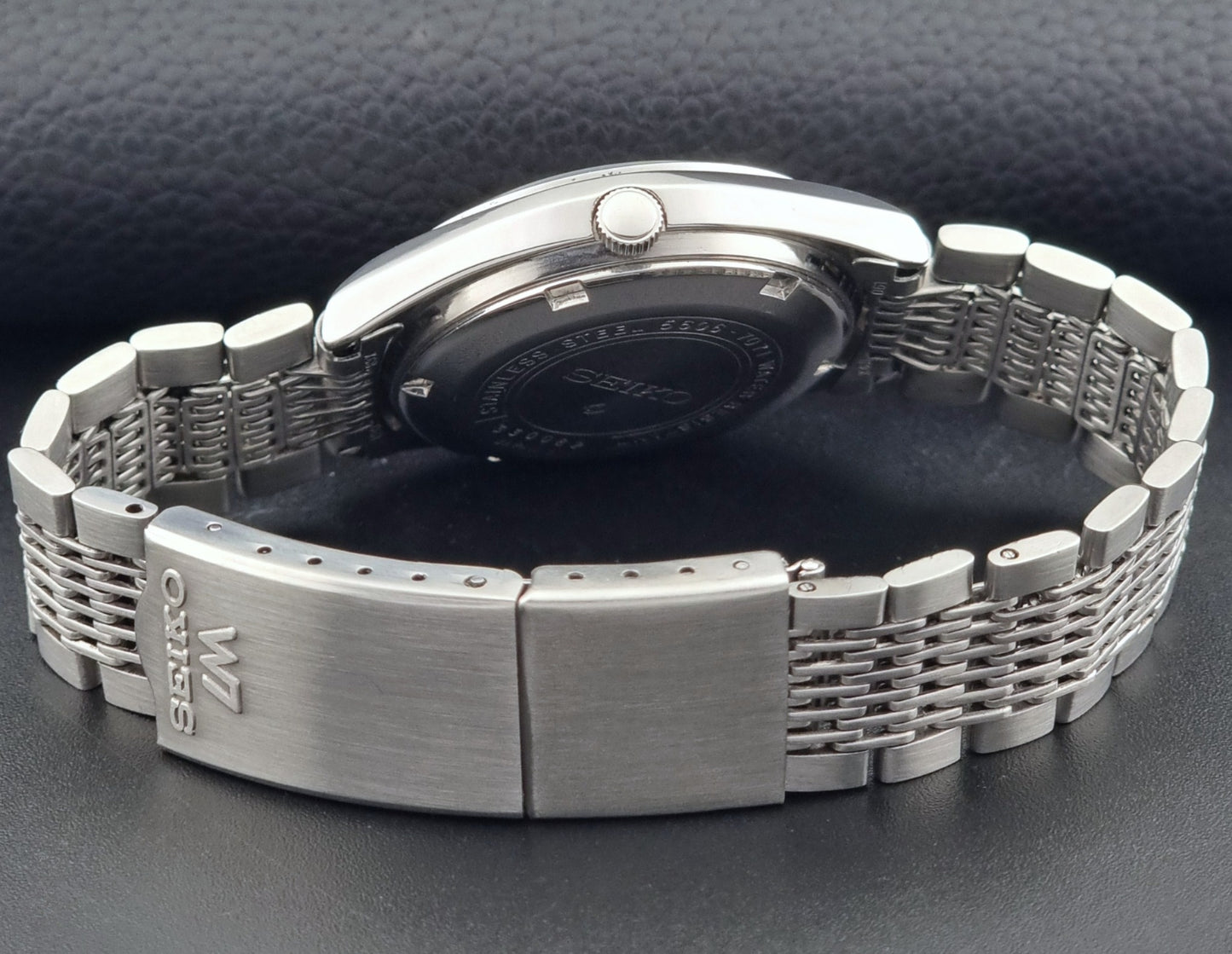 Vintage Seiko 5606-7071 LordMatic wristwatch with a metallic band on a dark gray background clasp view