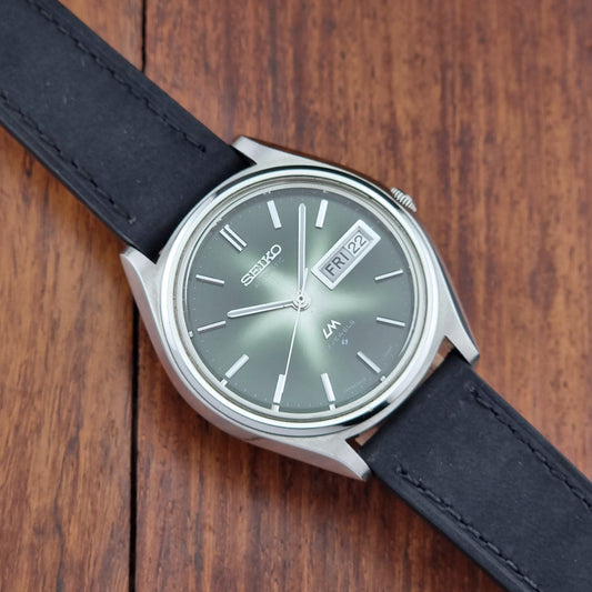 Vintage Seiko Lord Matic watch with a black strap on a wooden surface