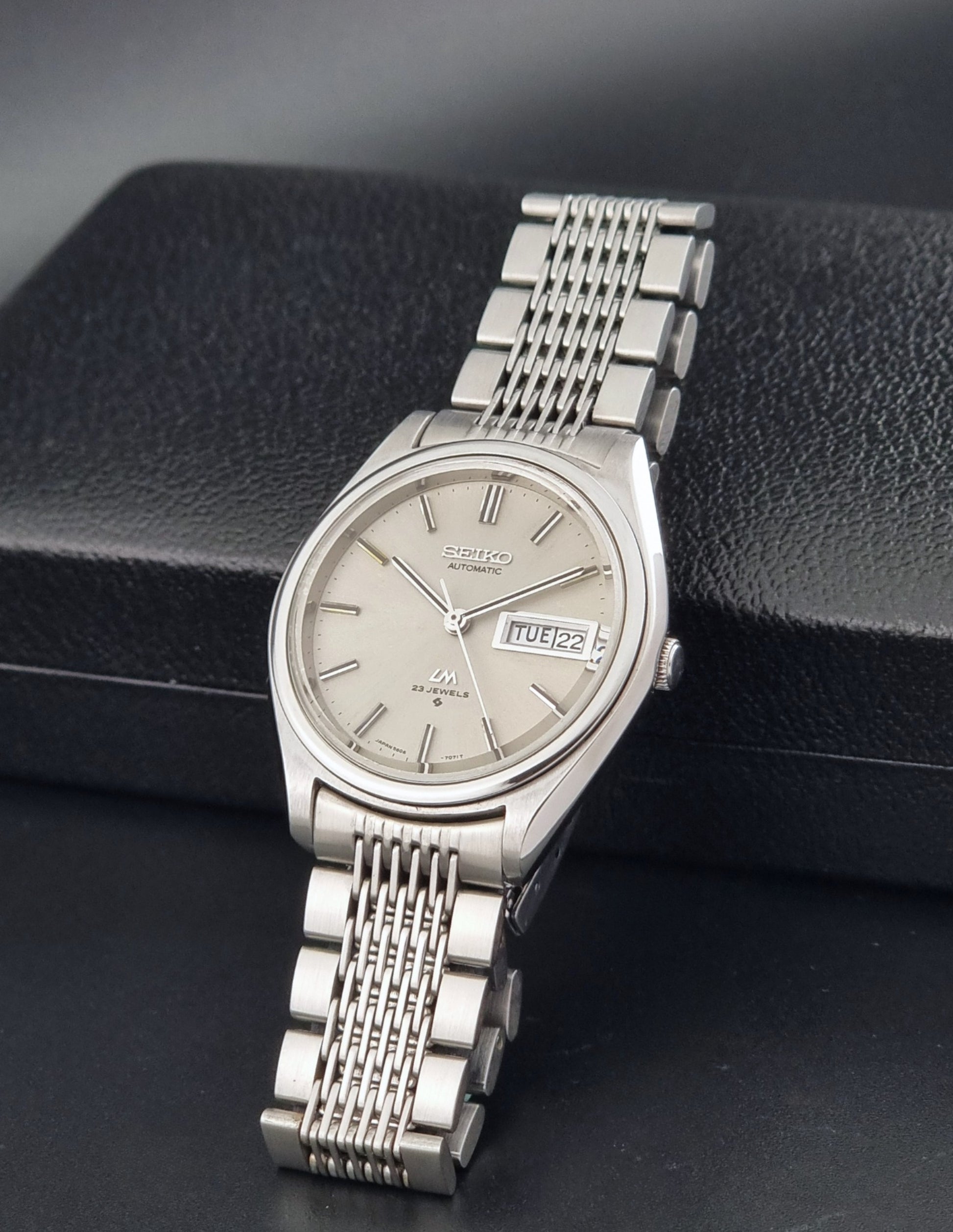 Vintage Seiko 5606-7071 watch LordMatic with a metallic band on a dark gray background crown view