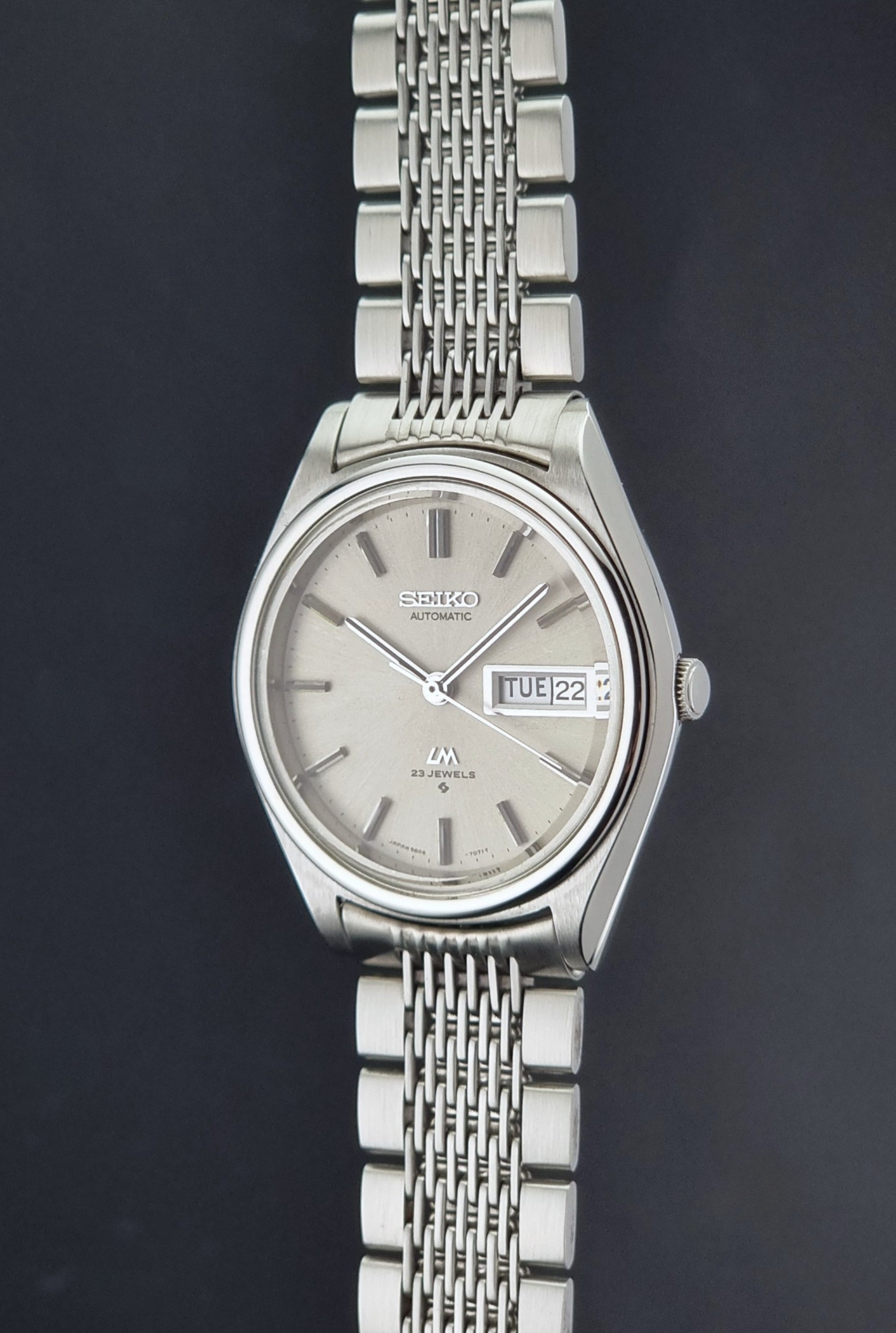Vintage Seiko 5606-7071 watch LordMatic with a metallic band on a dark gray background crown profile view