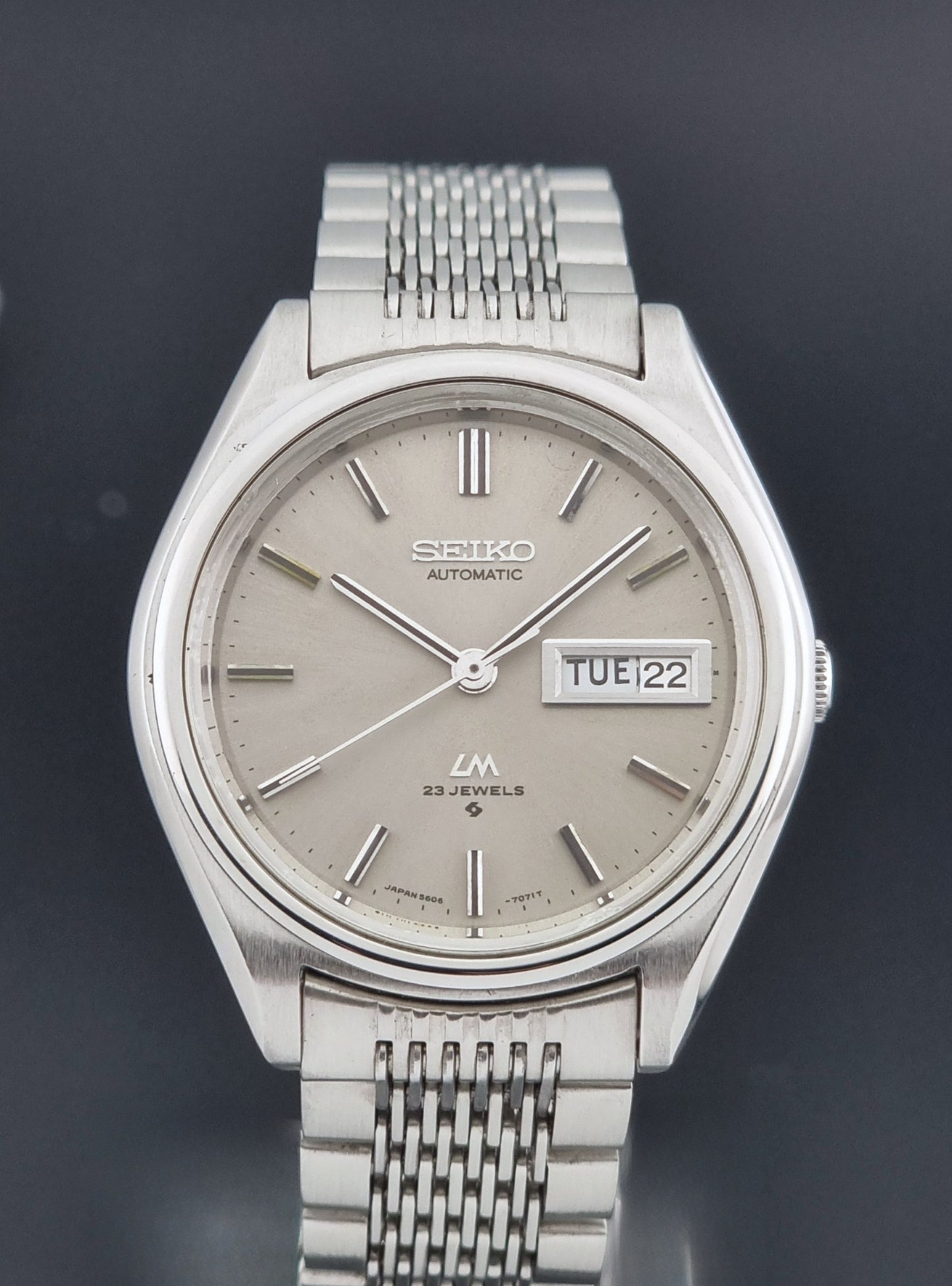 Vintage Seiko 5606-7071 watch LordMatic with a metallic band on a dark gray background close dial view