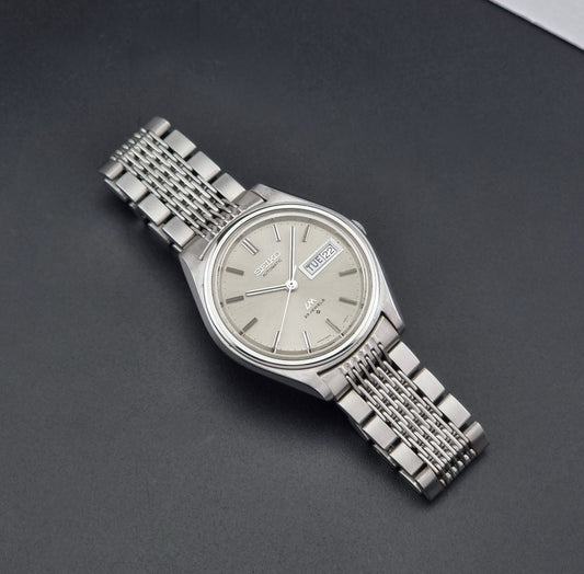 Vintage Seiko 5606-7071 watch LordMatic with a metallic band on a dark gray background dial