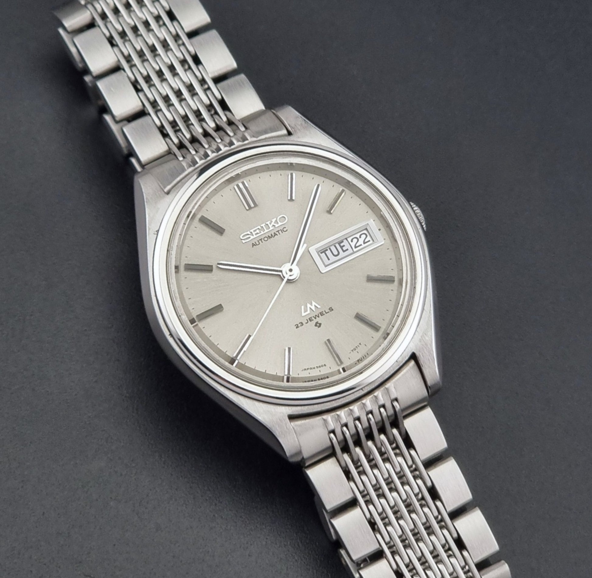 Vintage Seiko 5606-7071 watch LordMatic with a metallic band on a dark gray background front