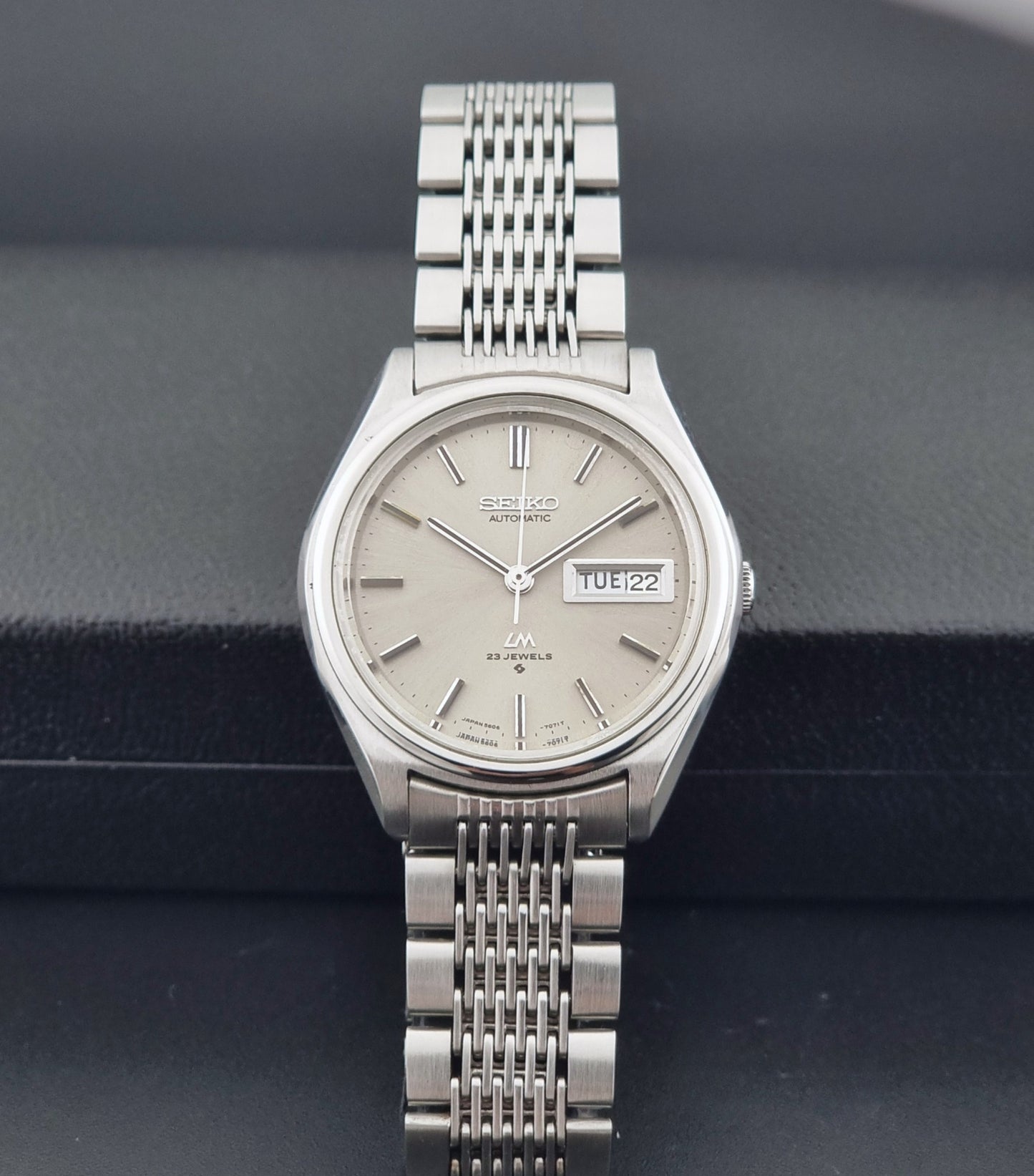 Vintage Seiko 5606-7071 watch LordMatic with a metallic band on a dark gray background dial view