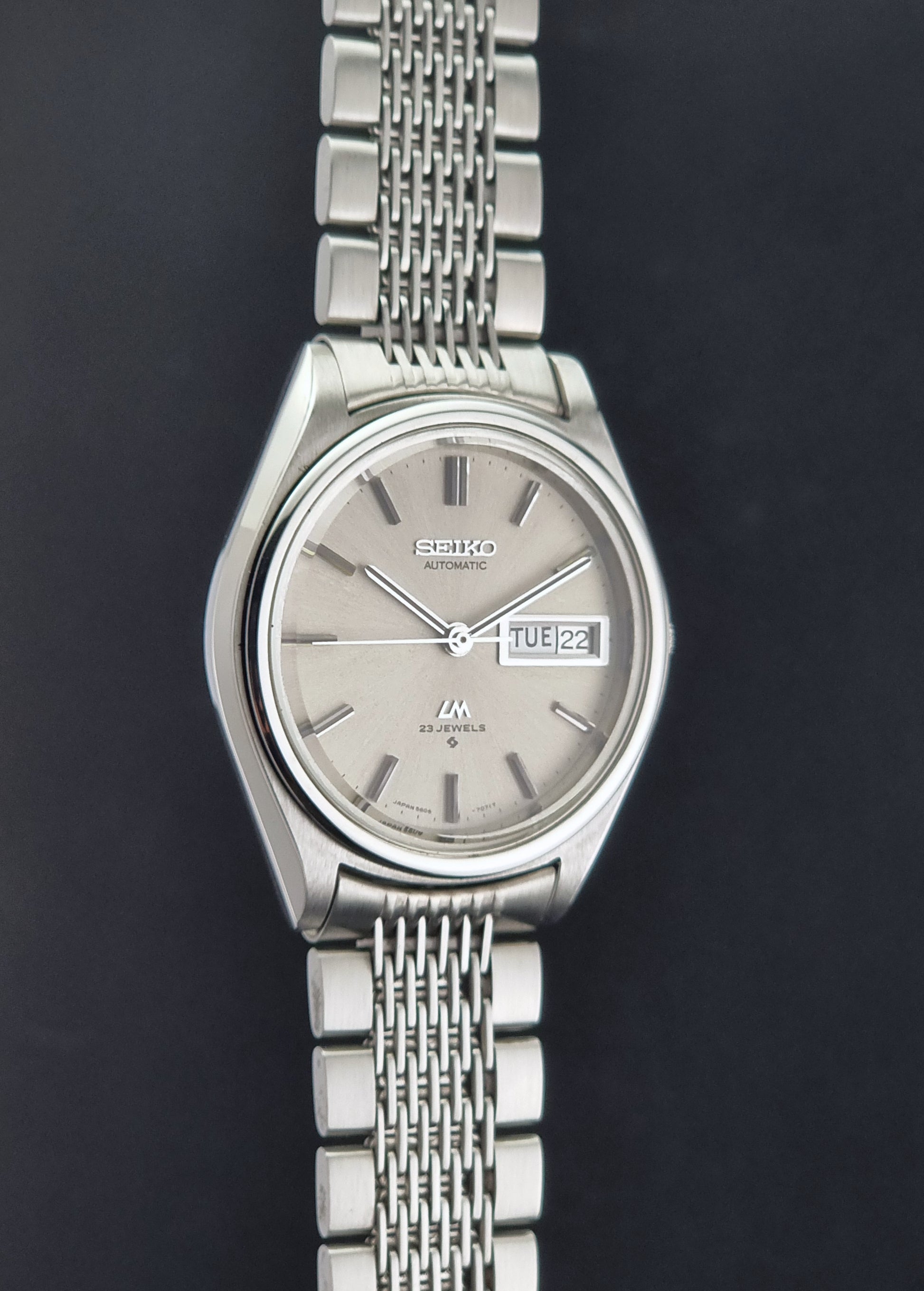 Vintage Seiko 5606-7071 watch LordMatic with a metallic band on a dark gray background side profile view