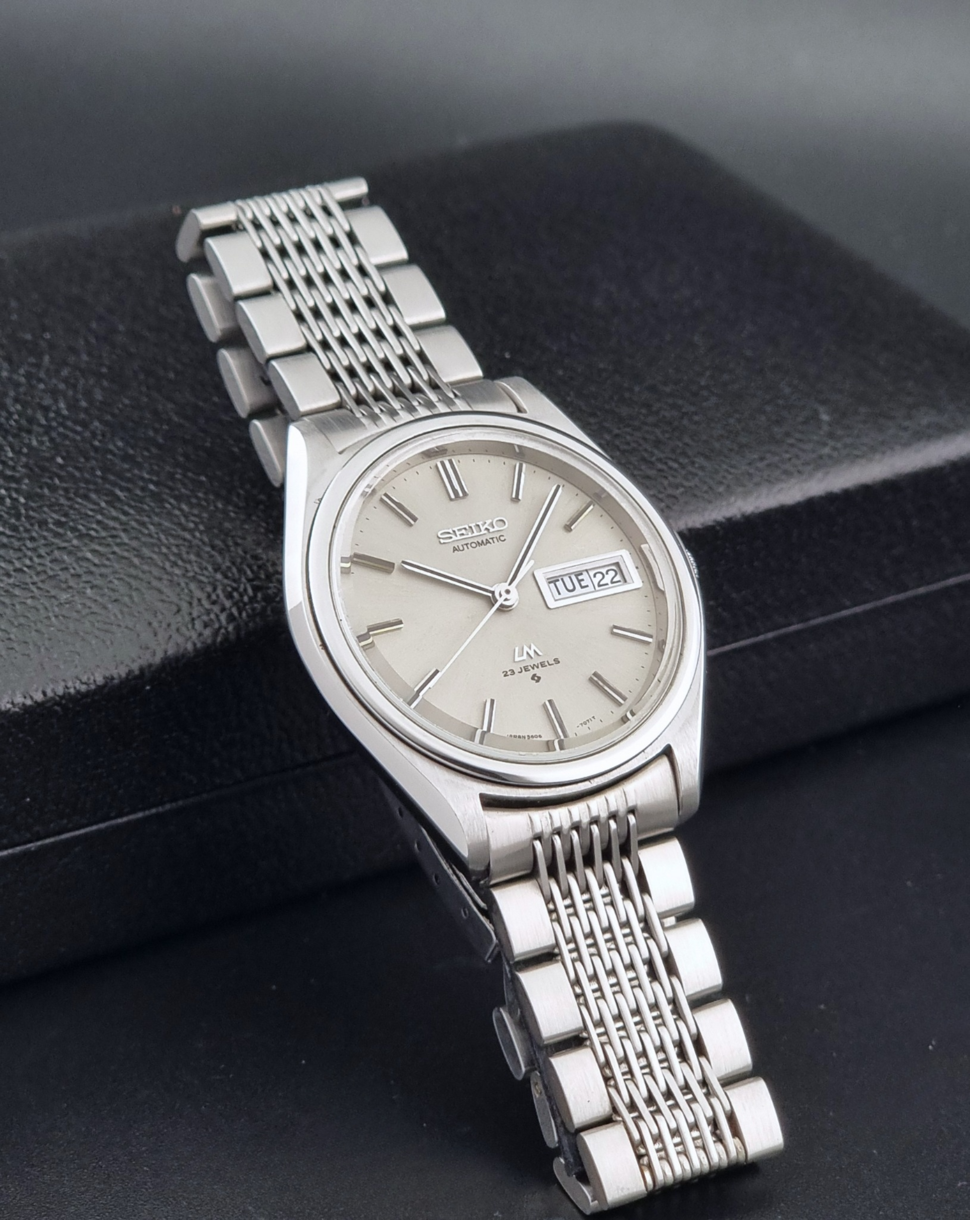 Vintage Seiko 5606-7071 watch LordMatic with a metallic band on a dark gray background side view