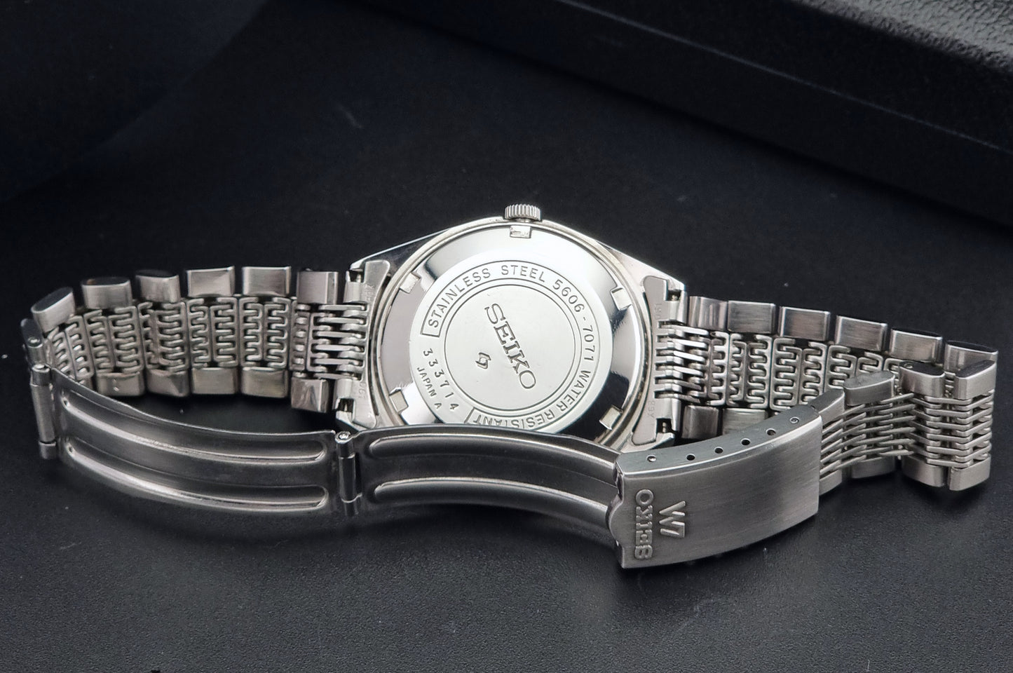 Vintage Seiko 5606-7071 watch LordMatic with a white dial and bracelet on a dark background clasp