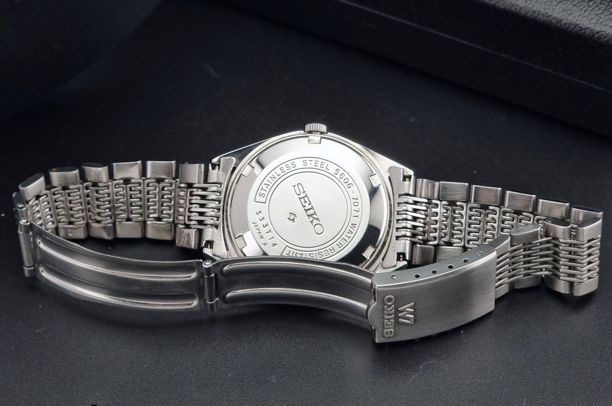 Vintage Seiko 5606-7071 watch LordMatic with a white dial and bracelet on a dark background clasp