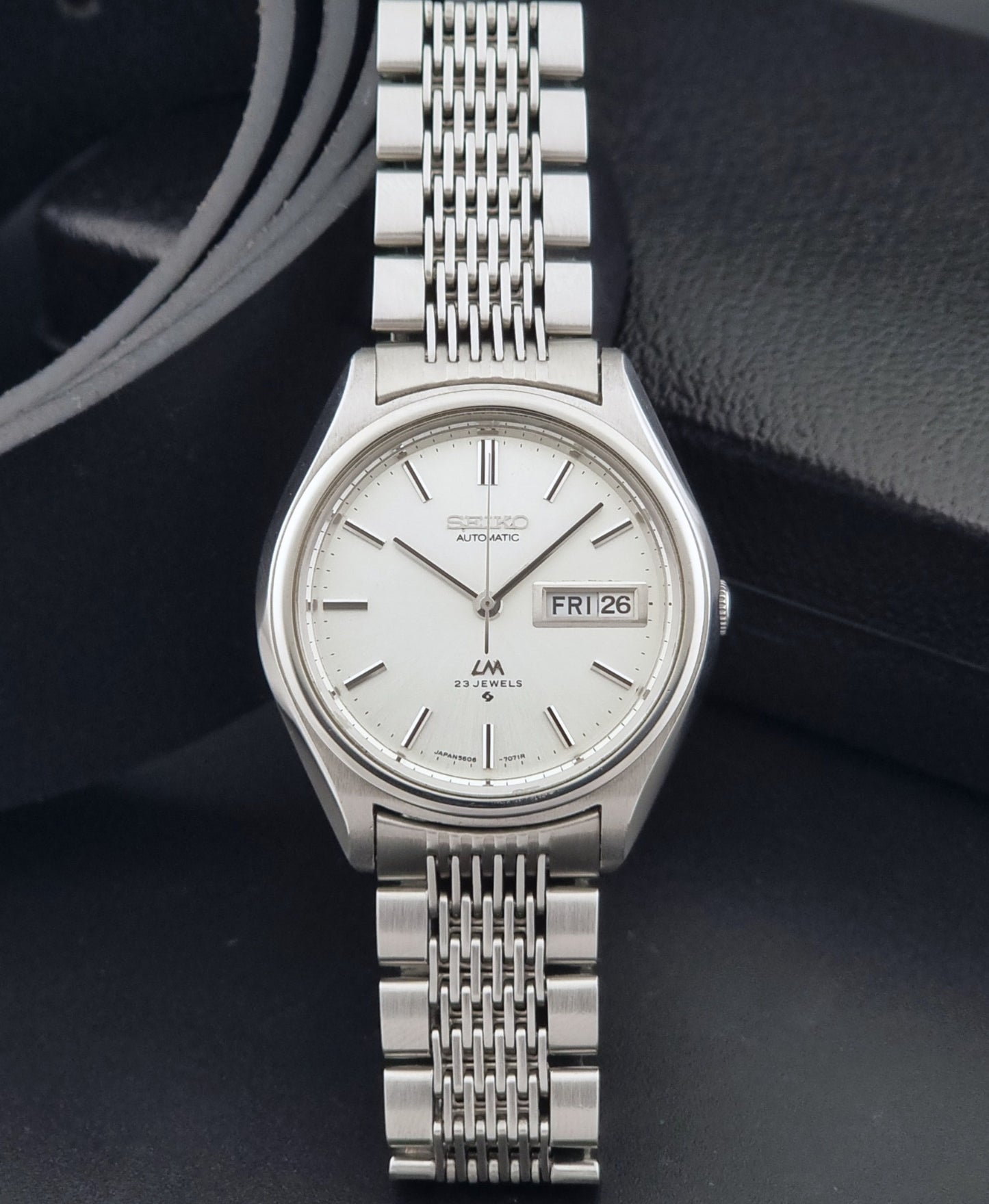 Vintage Seiko 5606-7071 watch LordMatic with a white dial and bracelet on a dark background dial view