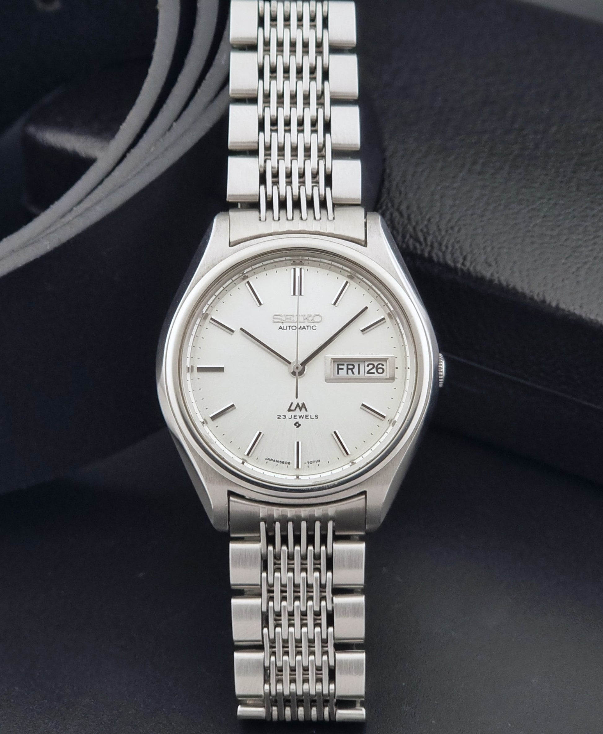 Vintage Seiko 5606-7071 watch LordMatic with a white dial and bracelet on a dark background dial view