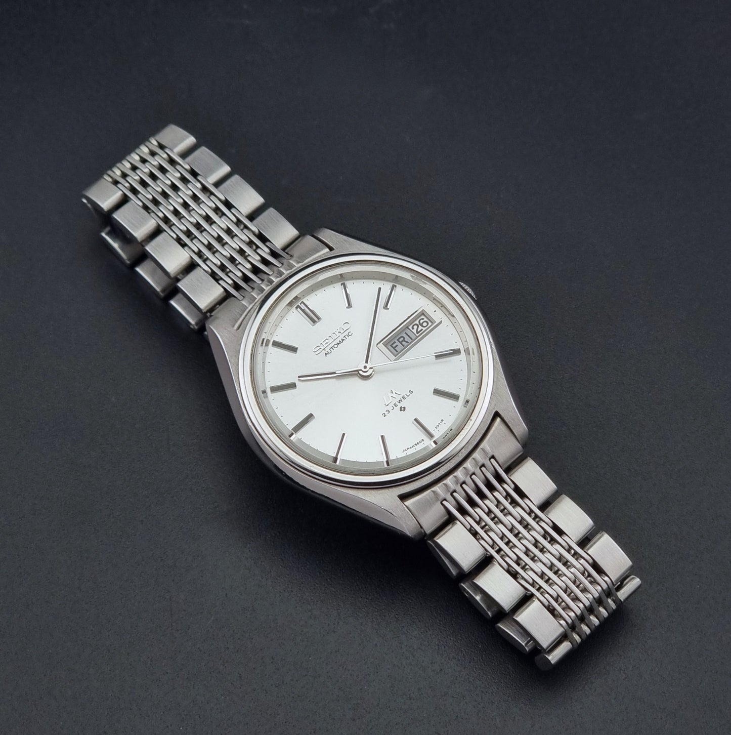 Vintage Seiko 5606-7071 watch LordMatic with a white dial and bracelet on a dark background dial