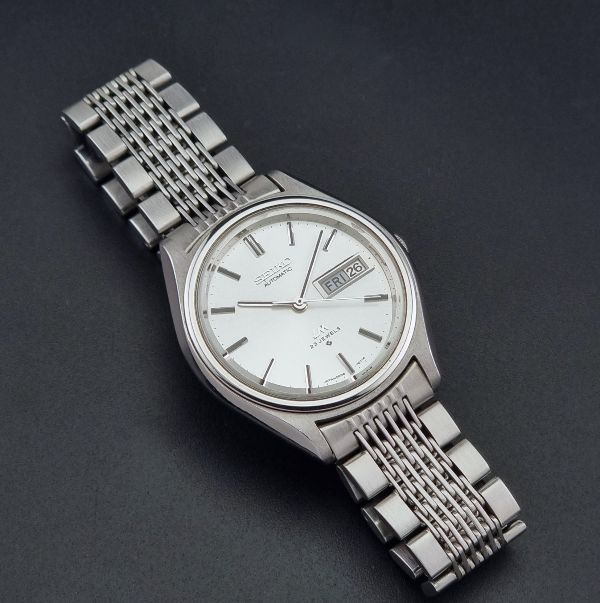 Vintage Seiko 5606-7071 watch LordMatic with a white dial and bracelet on a dark background close up dial view