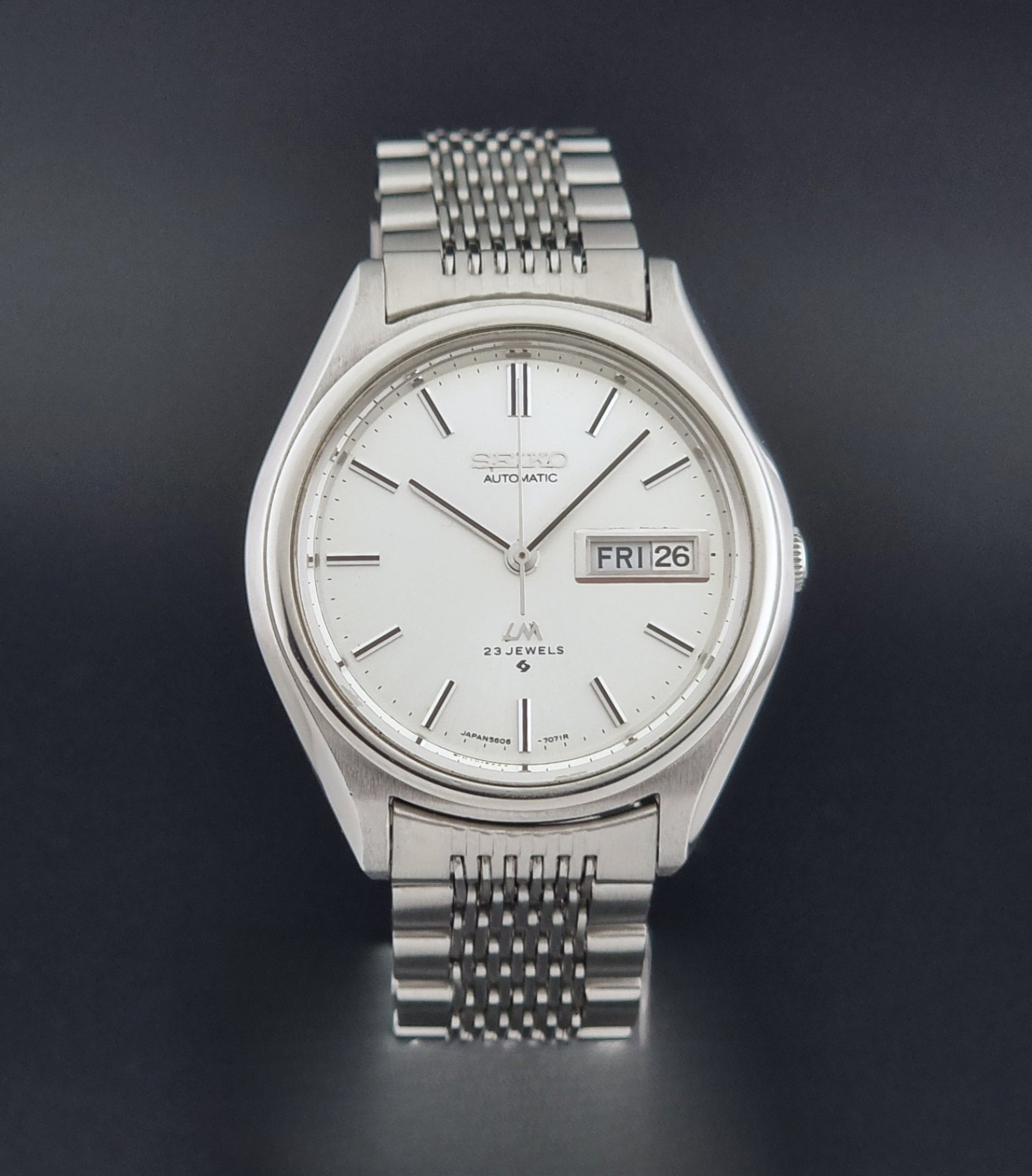 Vintage Seiko 5606-7071 watch LordMatic with a white dial and bracelet on a dark background close dial view