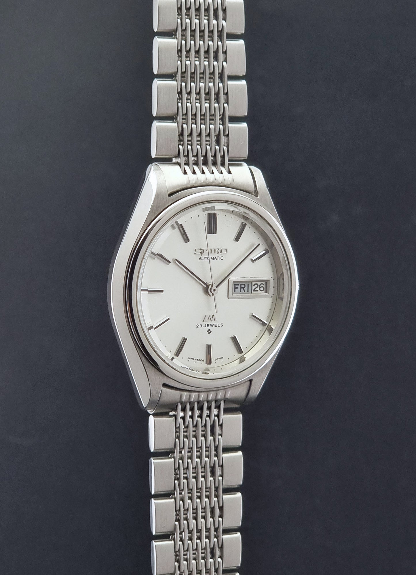 Vintage Seiko 5606-7071 watch LordMatic with a white dial and bracelet on a dark background side profiel view