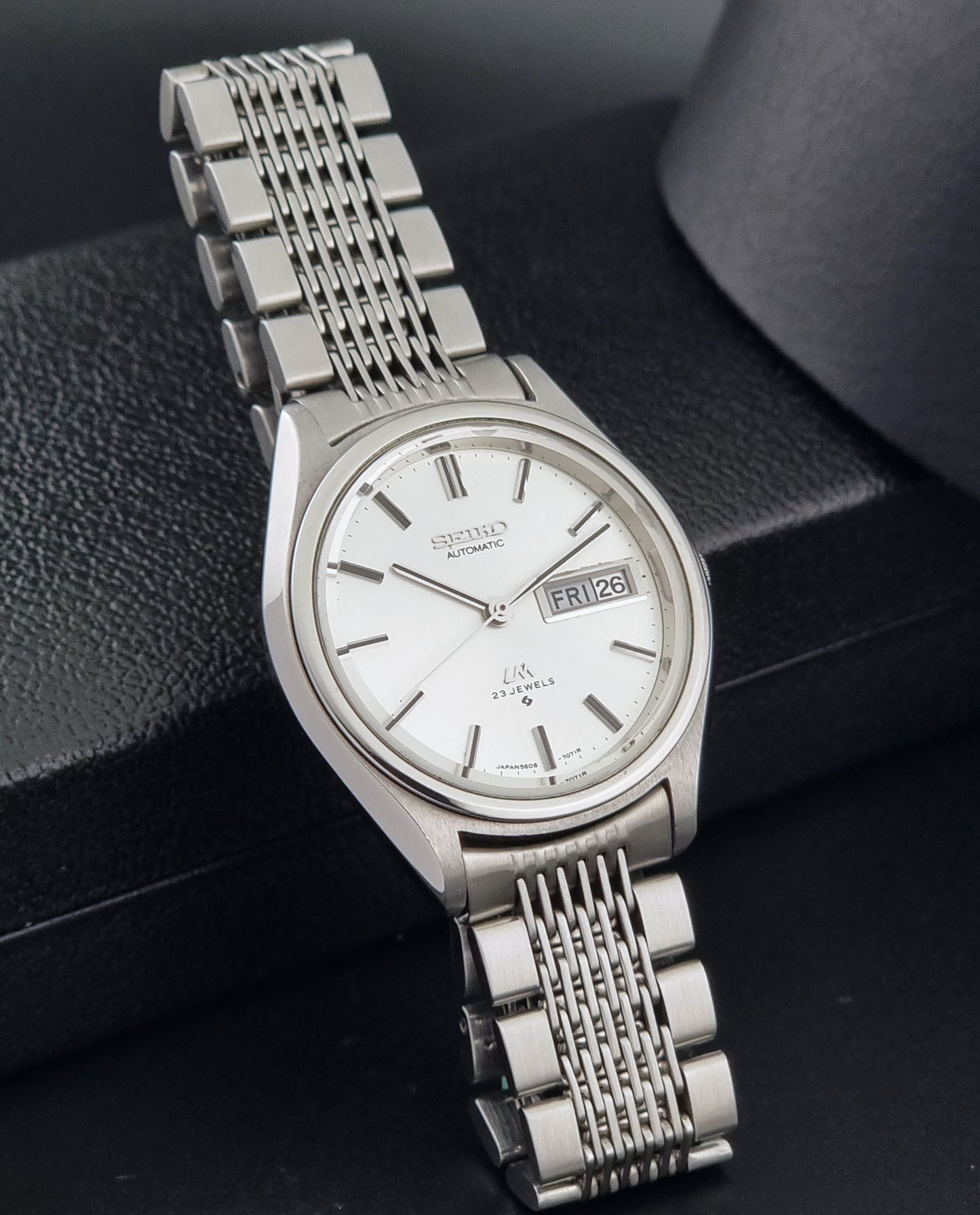 Vintage Seiko 5606-7071 watch LordMatic with a white dial and bracelet on a dark background side view