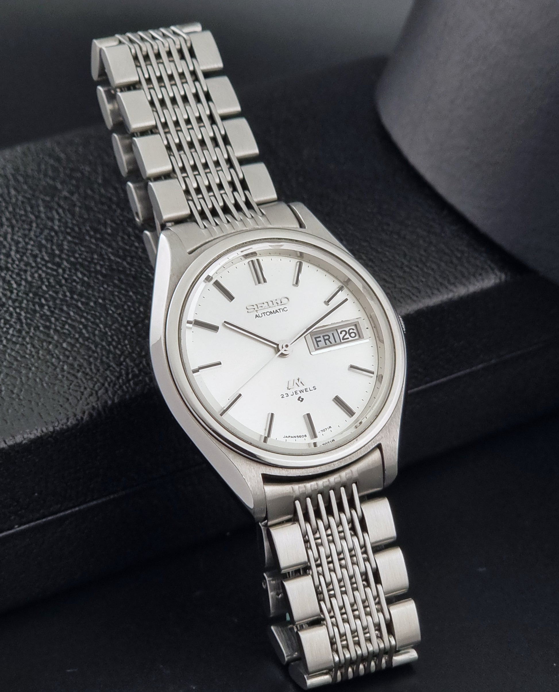 Vintage Seiko 5606-7071 watch LordMatic with a white dial and bracelet on a dark background side view