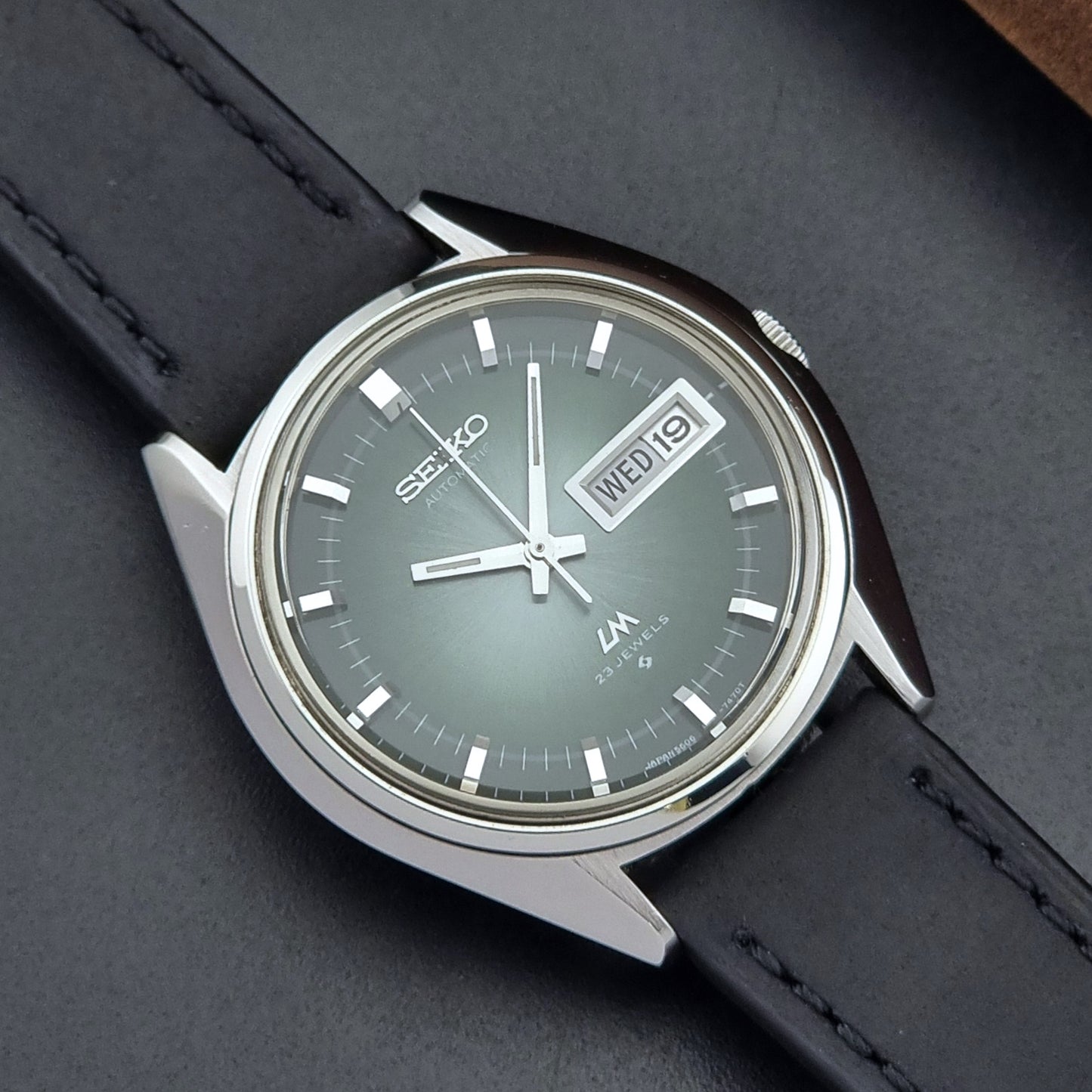 Vintage Seiko Wristwatch LordMatic 5606-7091 with a green face with black leather strap on a dark background dial view