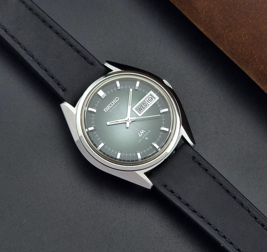 Vintage Seiko Wristwatch LordMatic 5606-7091 with a green face with black leather strap on a dark background front