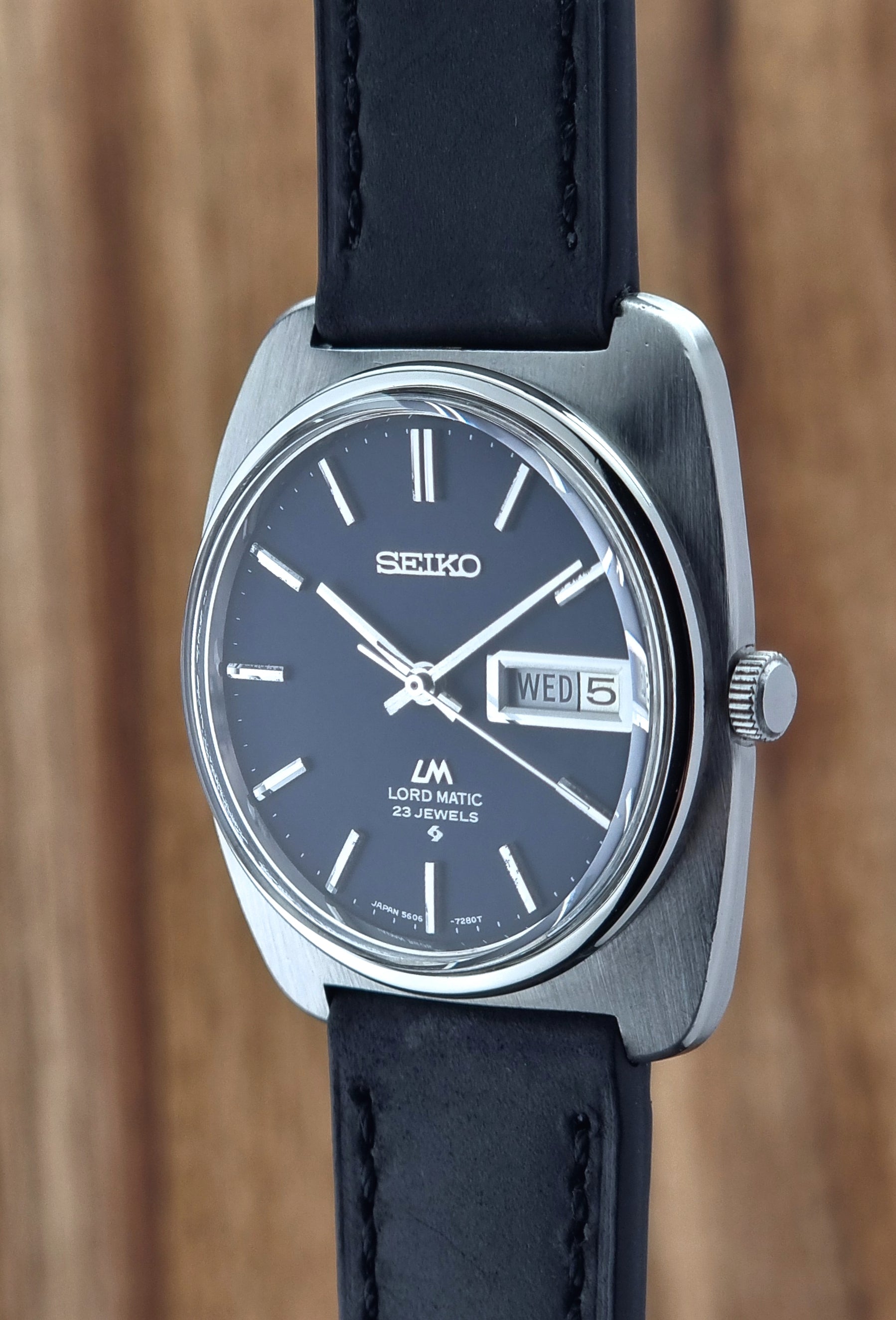 Seiko watch with black leather strap on a wooden background