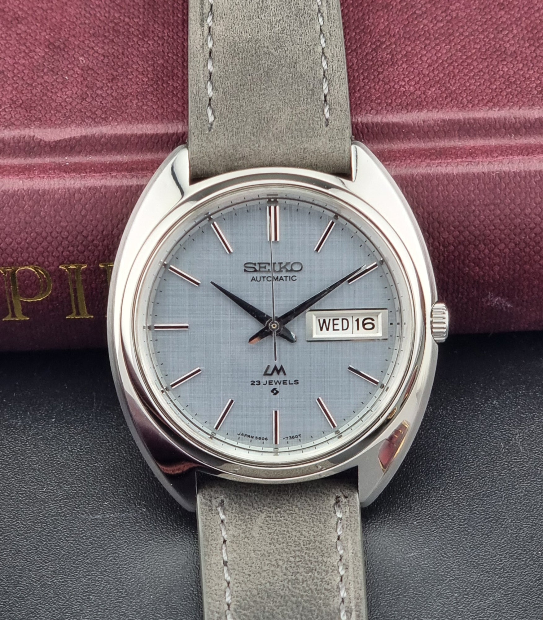 Seiko watch with gray strap on a dark surface