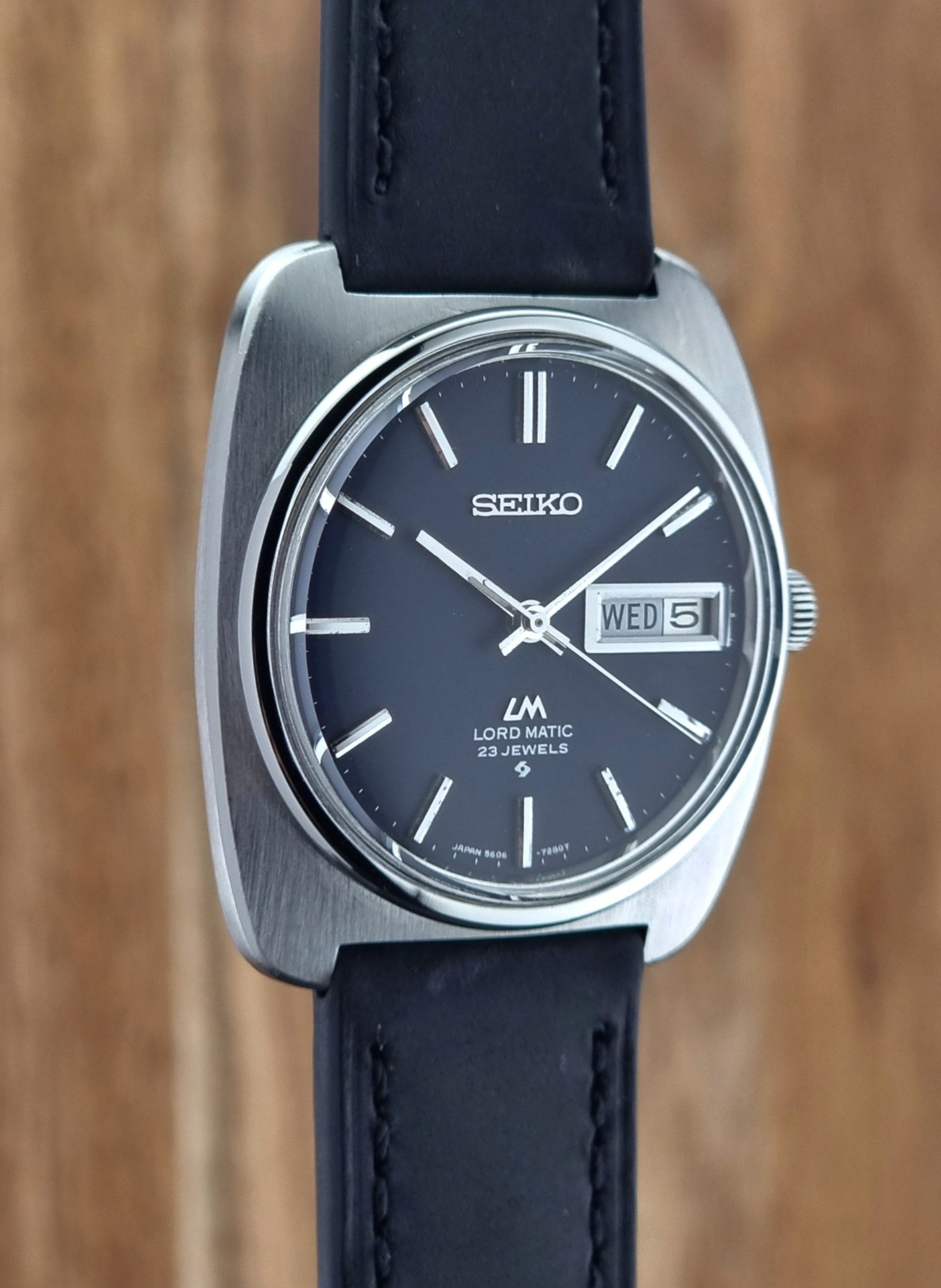 Seiko watch with black leather strap on a wooden background