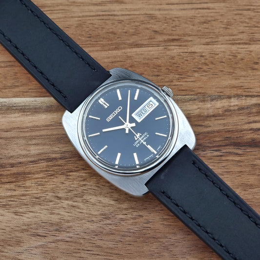 Seiko watch with black strap on a wooden surface