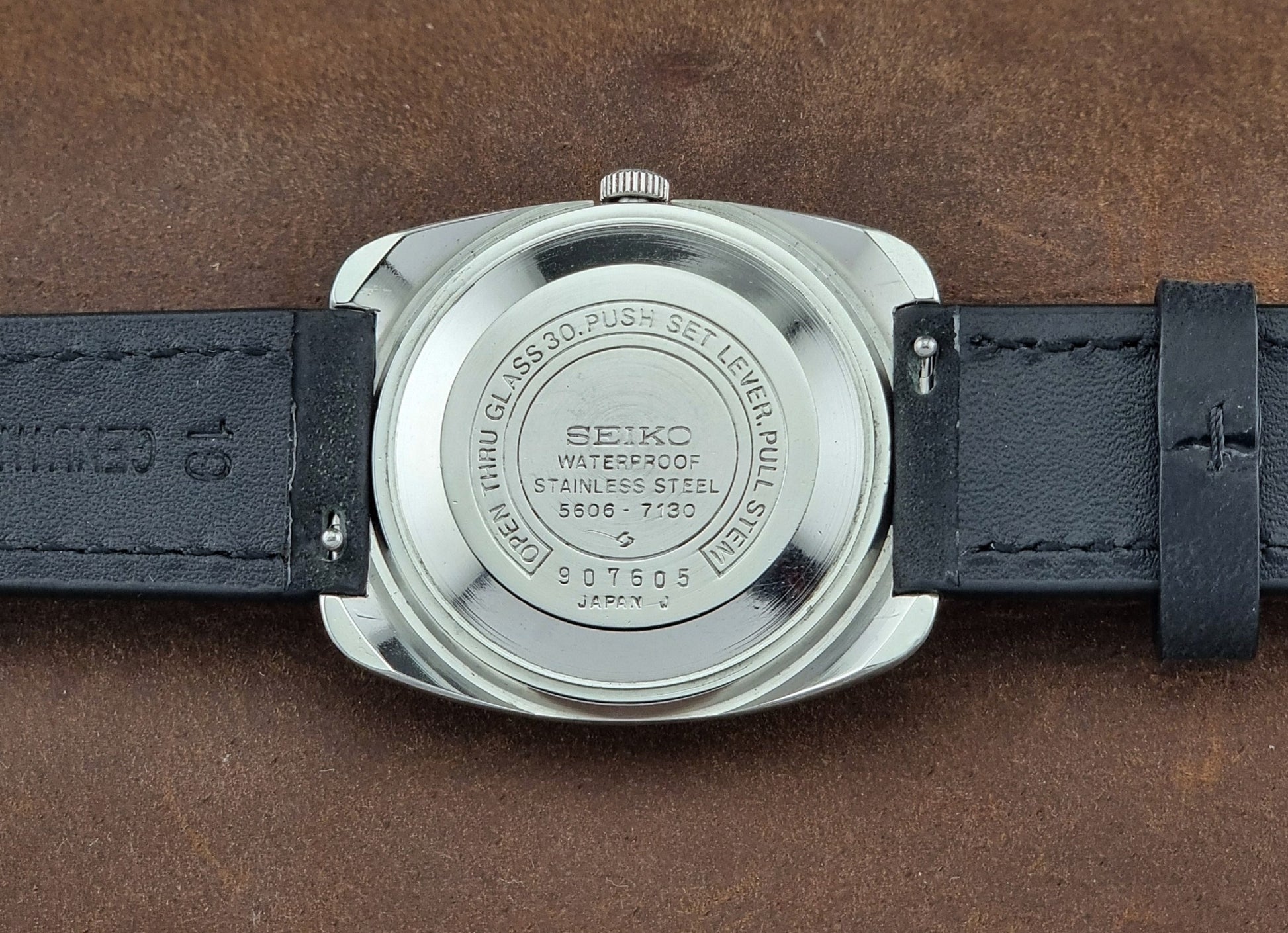 Seiko watch back on a brown leather background