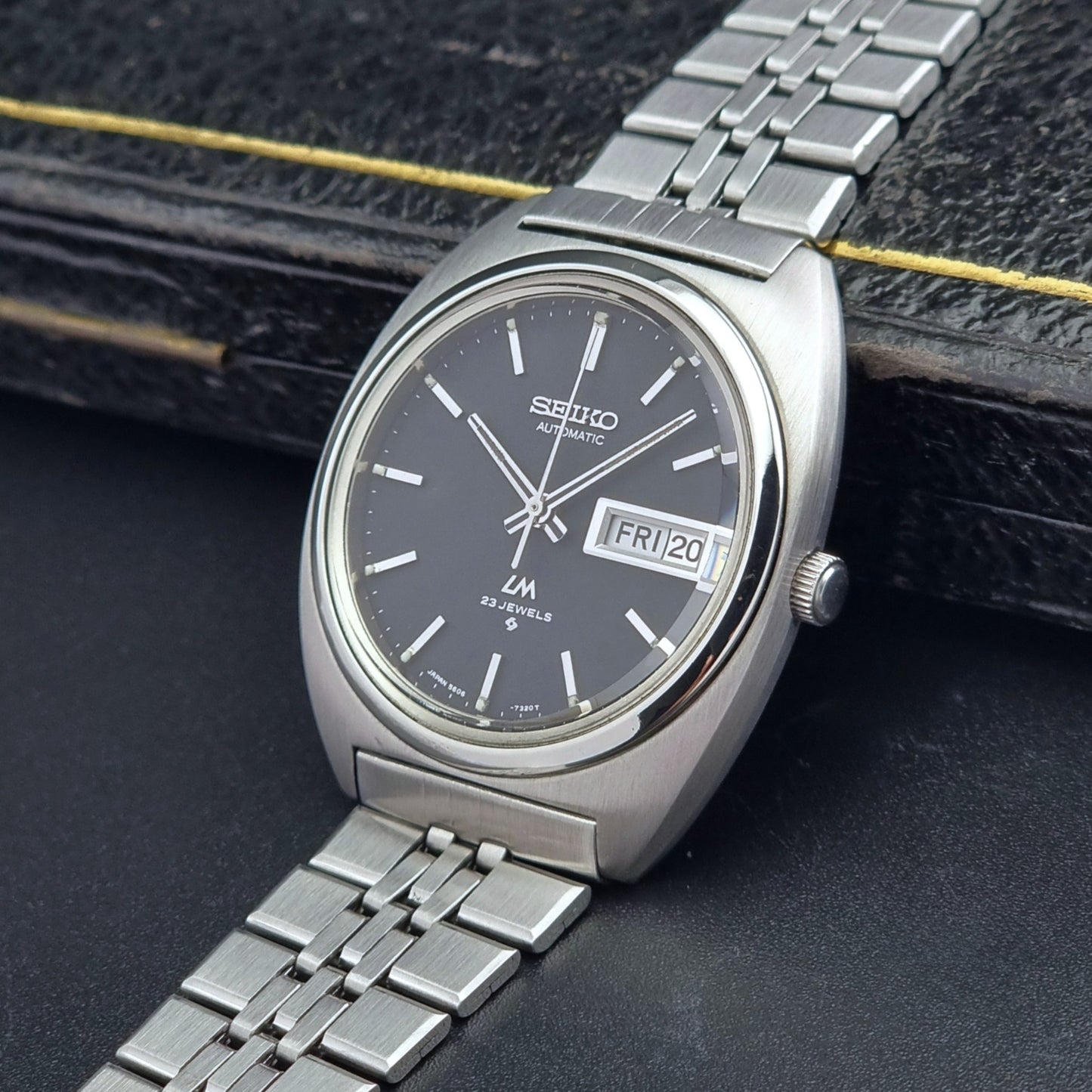 Vintage Seiko Lordmatic 5606-7140 watch with black dial on a dark textured surface