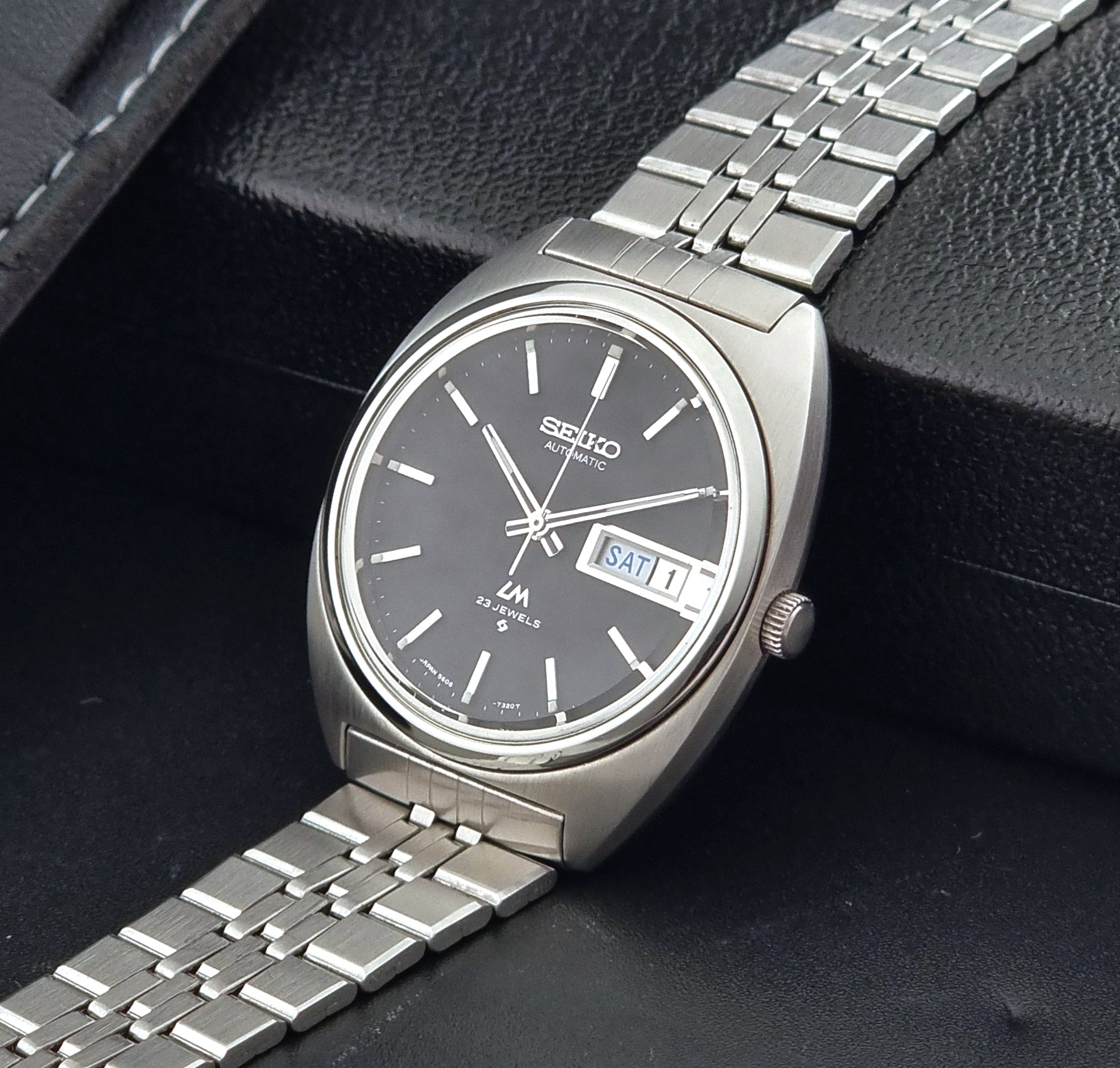 Seiko Wristwatch LordMatic 5606-7140 Vintage watch with a black face on a dark background crown view