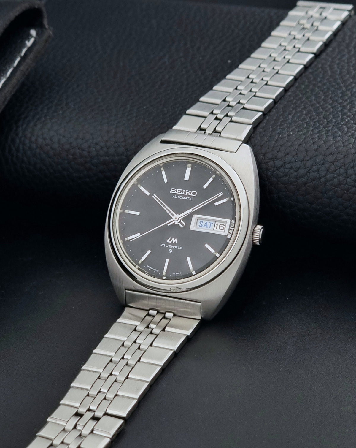 Vintage Seiko Wristwatch LordMatic 5606-7140 with  stainless steel bracelet on a dark background crown view