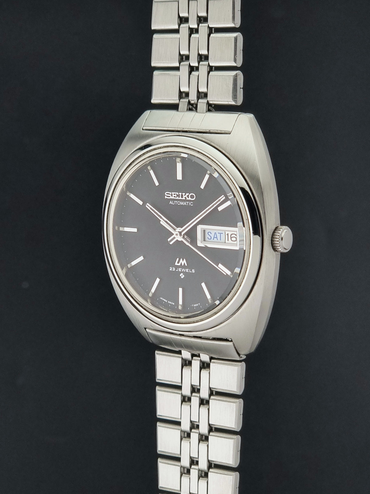 Vintage Seiko Wristwatch LordMatic 5606-7140 with  stainless steel bracelet on a dark background crown profile view