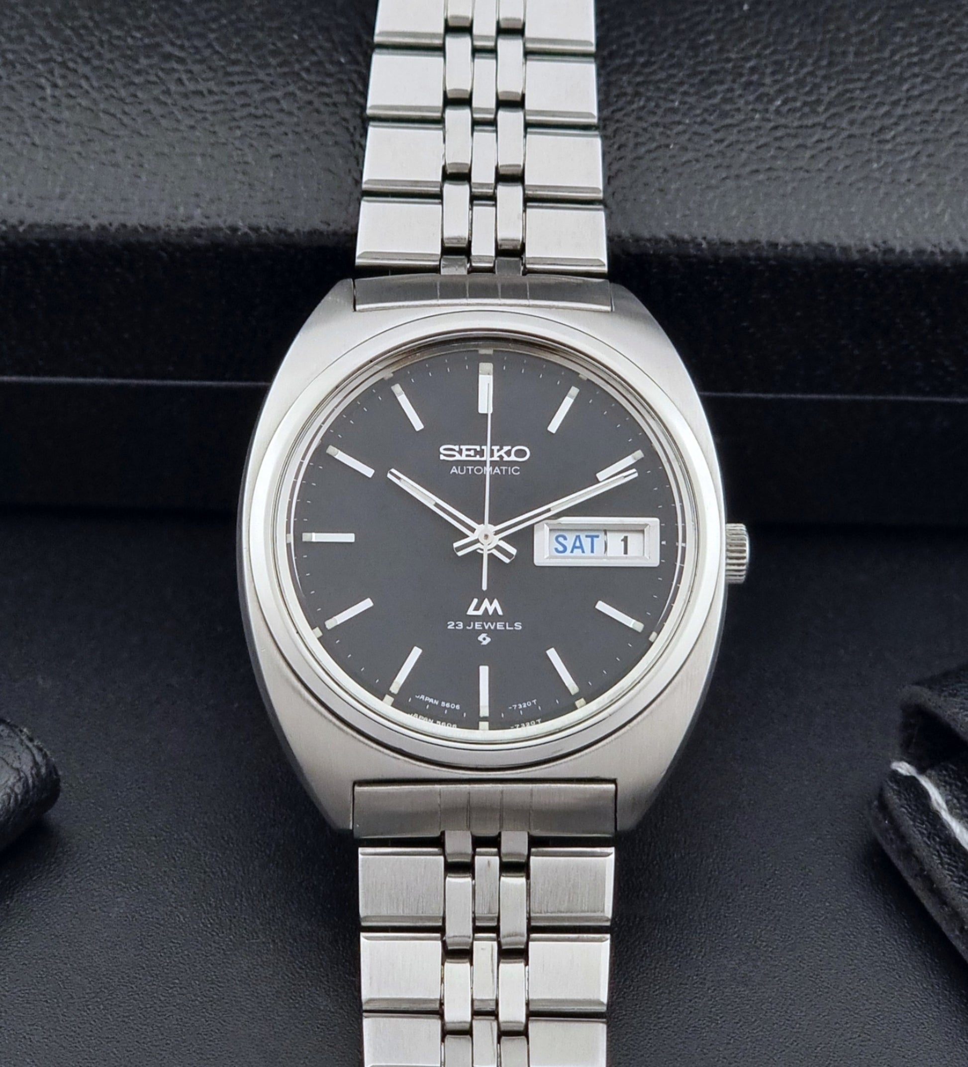 Seiko Wristwatch LordMatic 5606-7140 Vintage watch with a black face on a dark background dial view