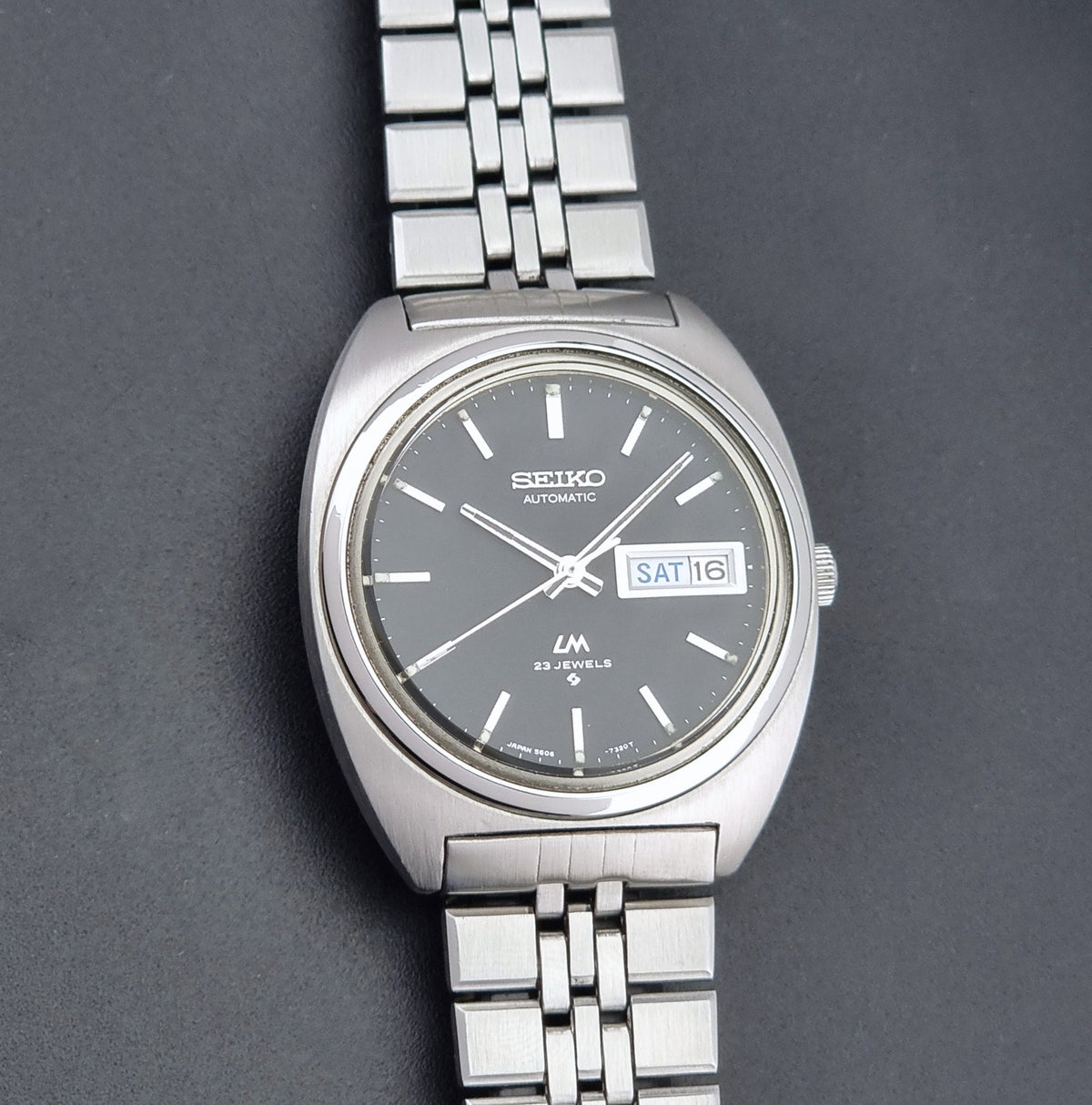 Vintage Seiko Wristwatch LordMatic 5606-7140 with  stainless steel bracelet on a dark background front view