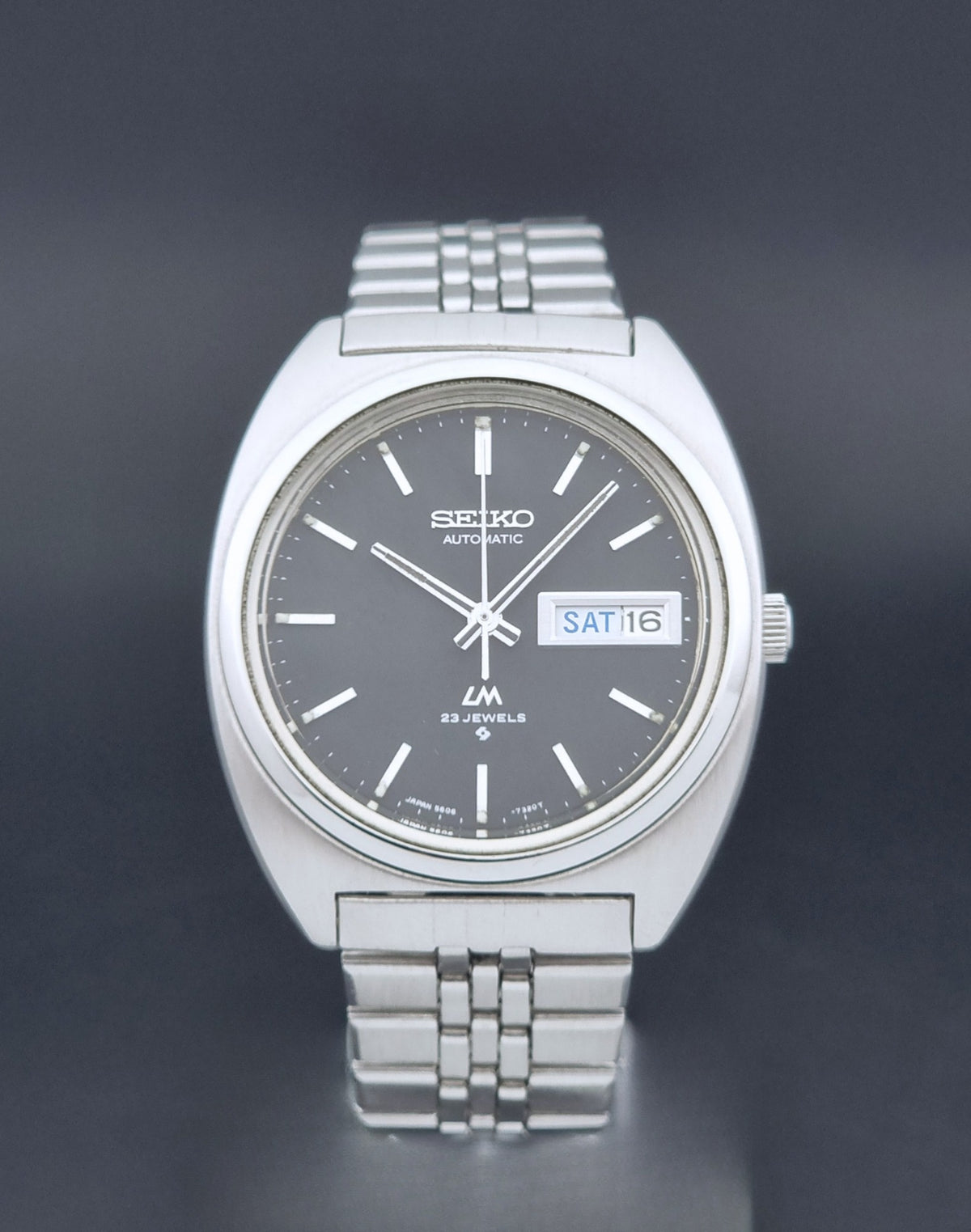 Vintage Seiko Wristwatch LordMatic 5606-7140 with  stainless steel bracelet on a dark background front view