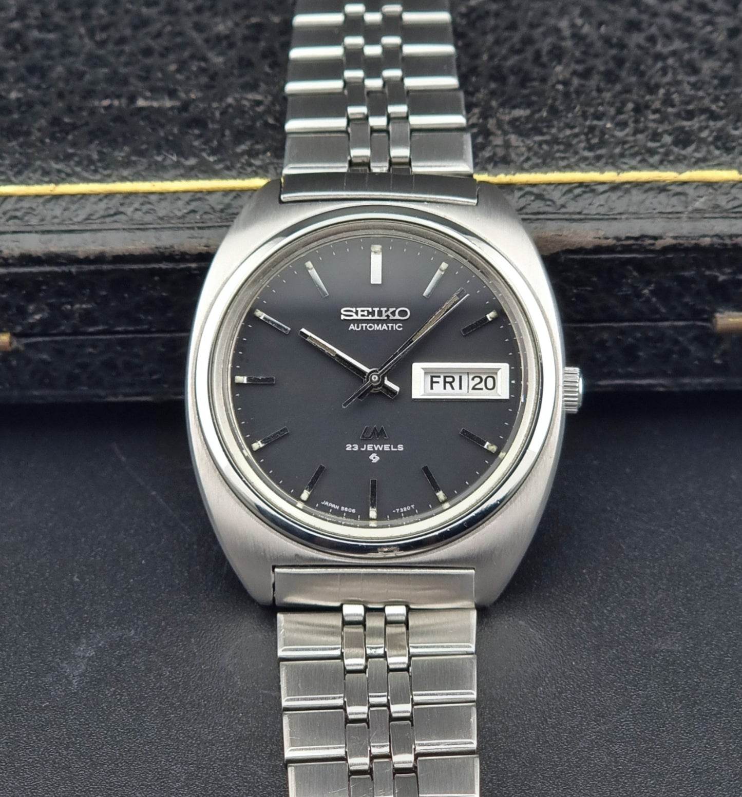 Vintage Seiko Lordmatic 5606-7140 watch watch with black dial on a dark textured background