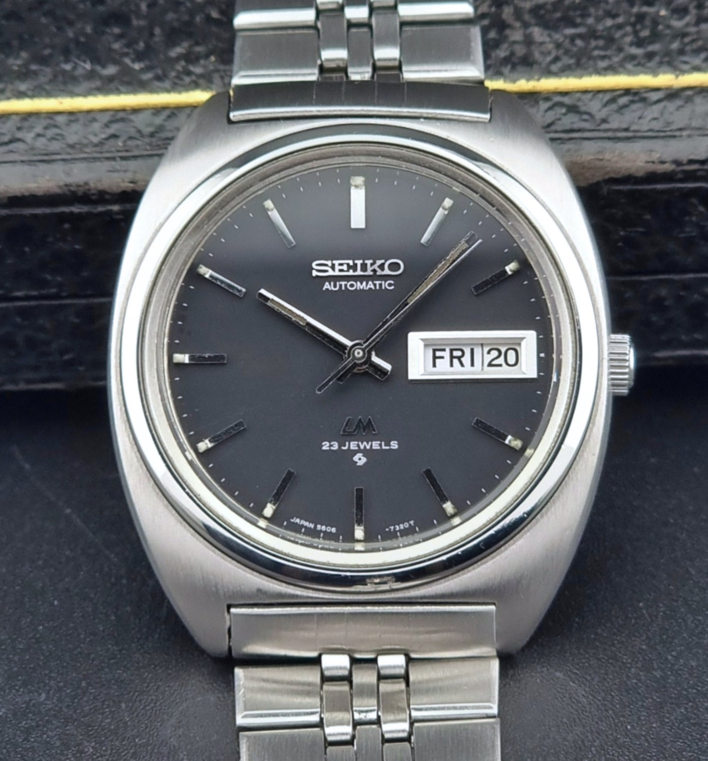 Vintage Seiko Lordmatic 5606-7140 watch with black dial on a dark textured background