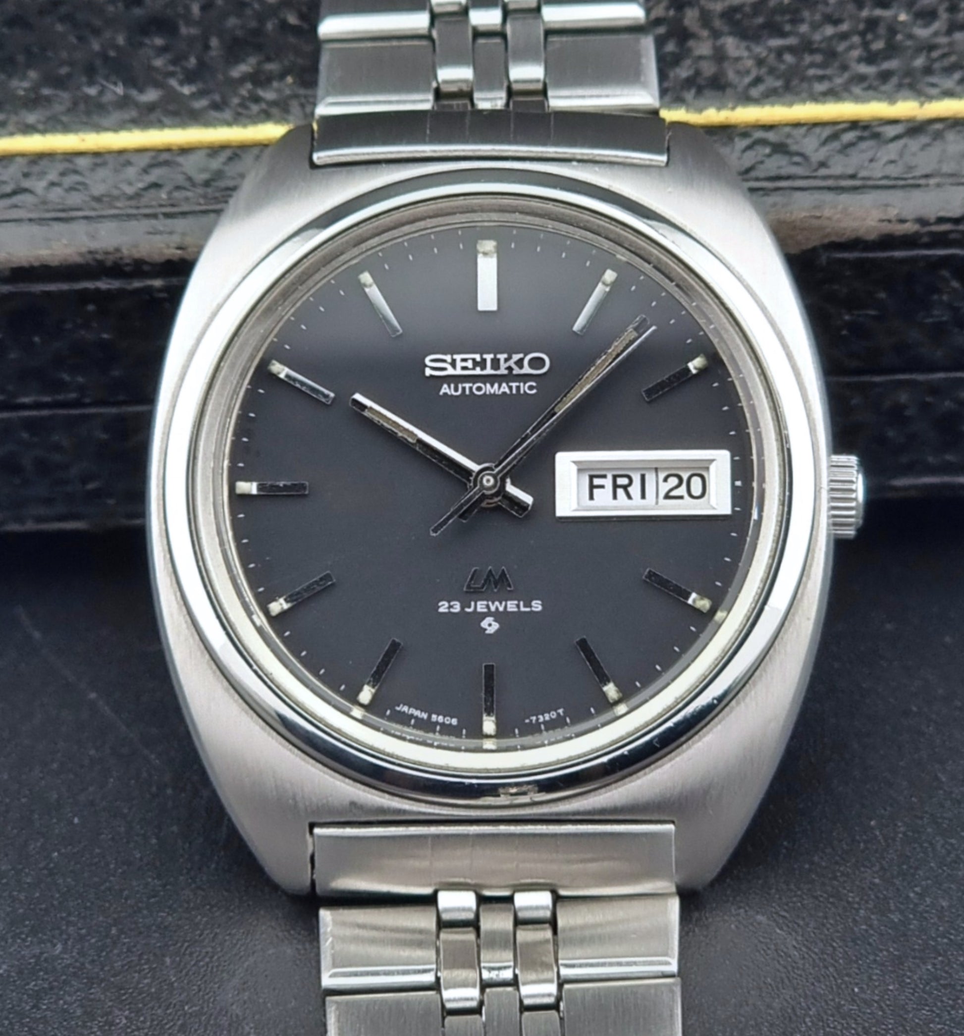 Vintage Seiko Lordmatic 5606-7140 watch with black dial on a dark textured background