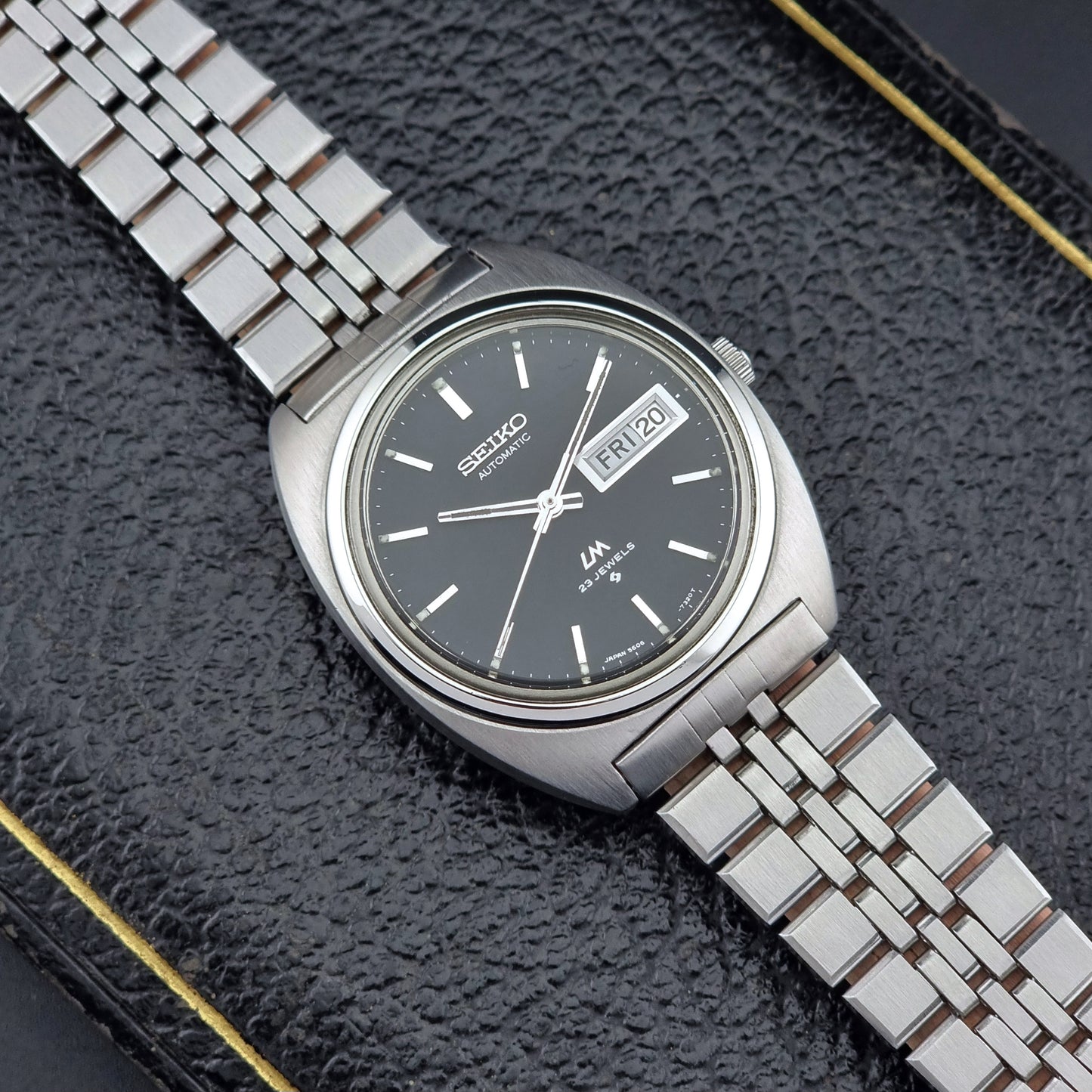 Vintage Seiko Lordmatic 5606-7140 watch with a dark face on a textured black surface