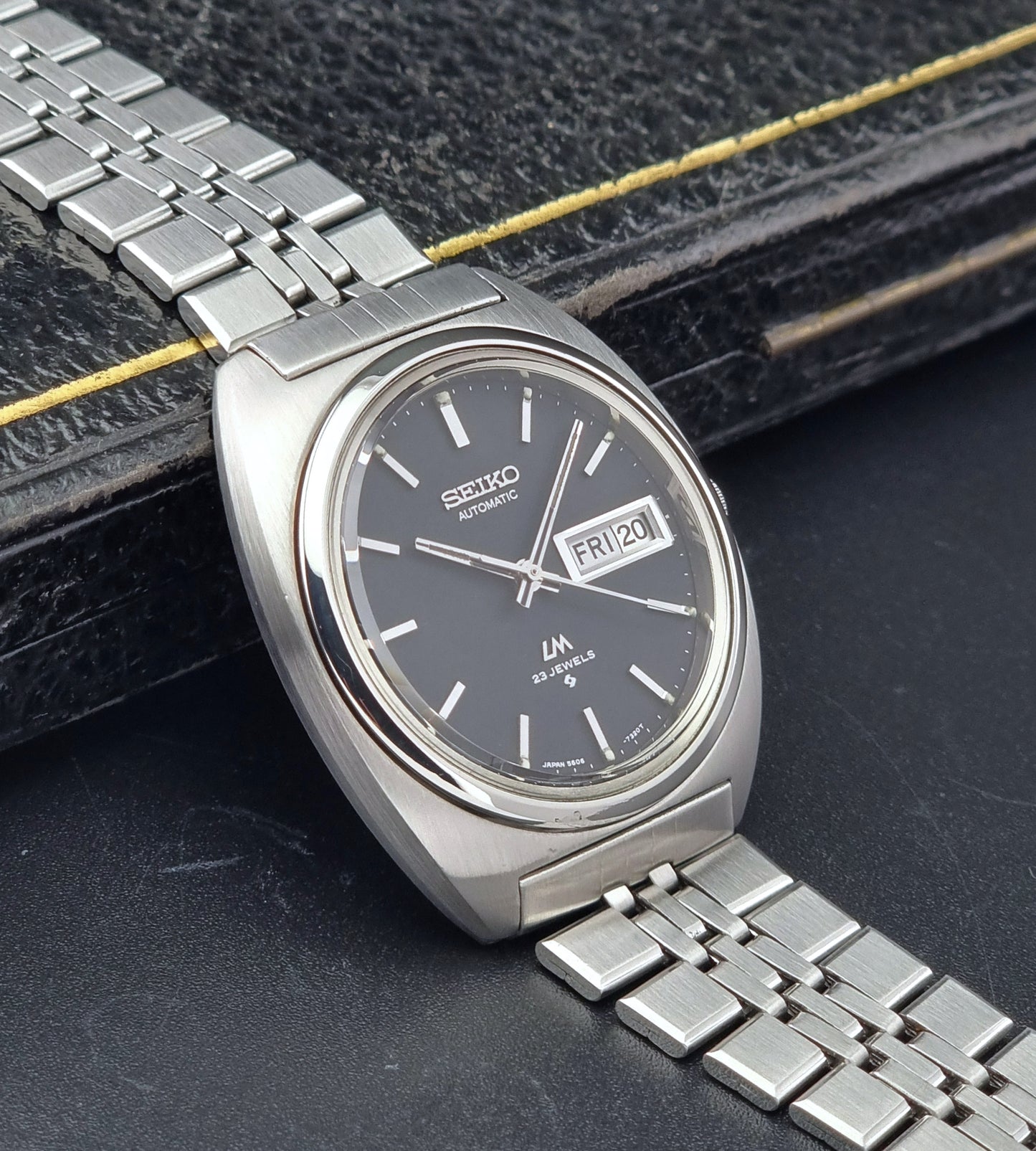 Vintage Seiko Lordmatic 5606-7140 watch with a dark face on a textured surface