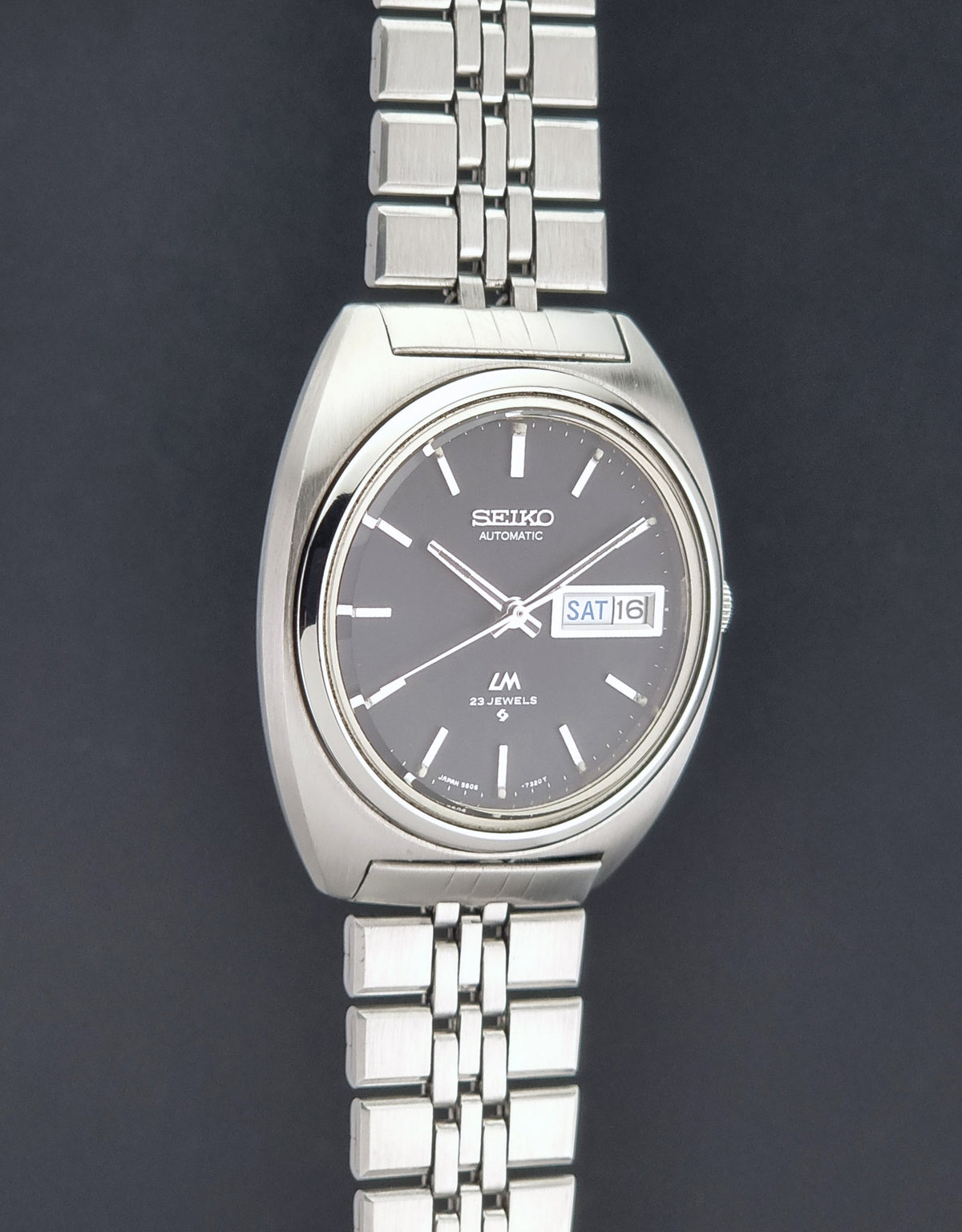 Vintage Seiko Wristwatch LordMatic 5606-7140 with  stainless steel bracelet on a dark background side profile view