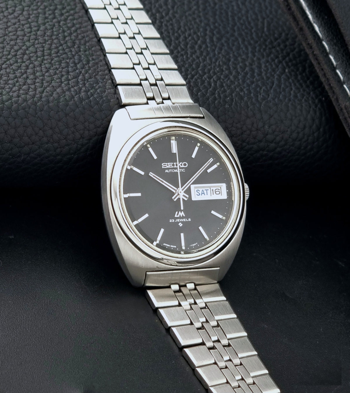 Vintage Seiko Wristwatch LordMatic 5606-7140 with  stainless steel bracelet on a dark background side view