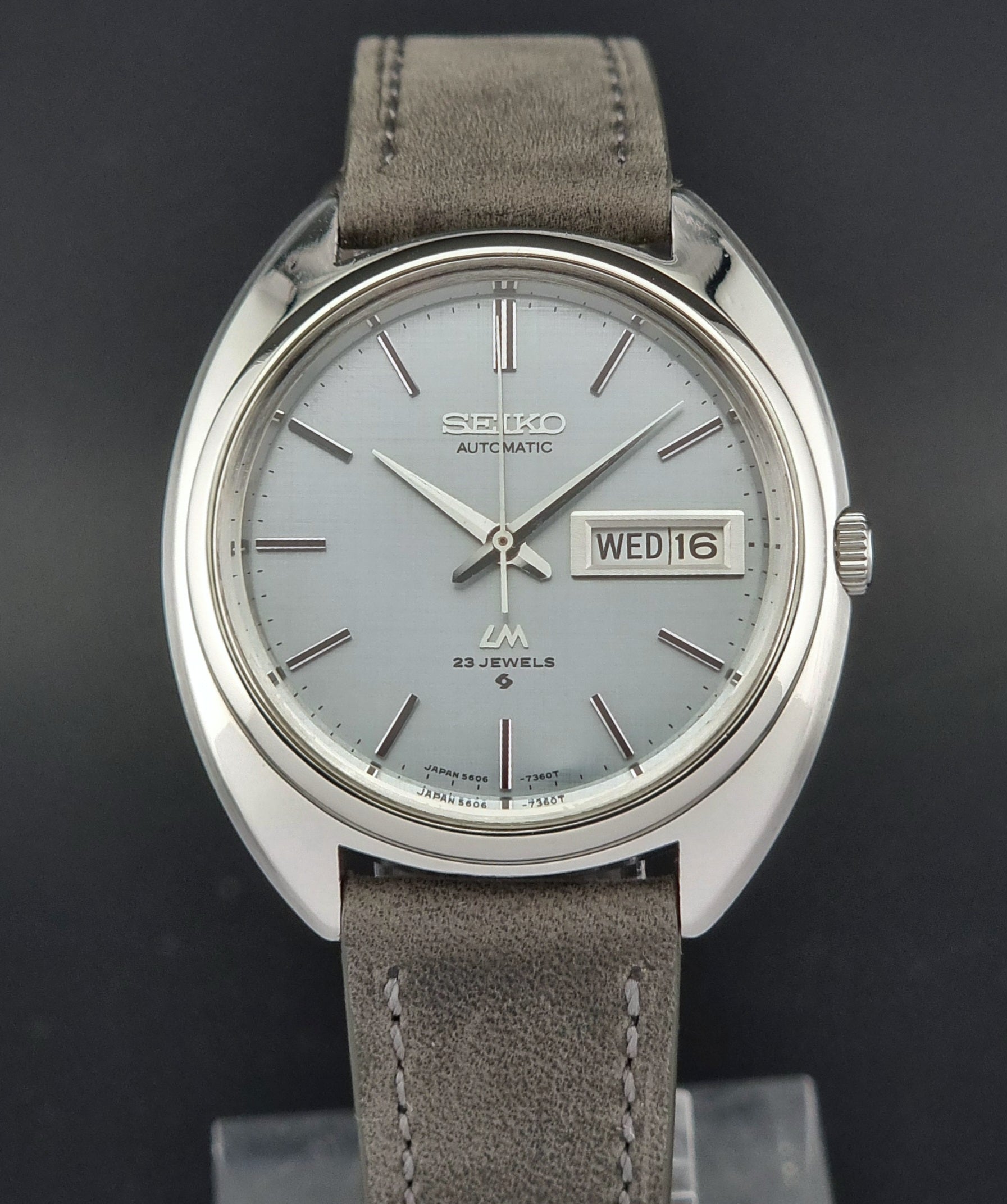 Seiko watch with gray strap and silver case on a dark background