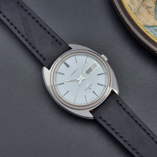Vintage Seiko Lord Matic 5606-7150 watch with black leather strap on a dark background 