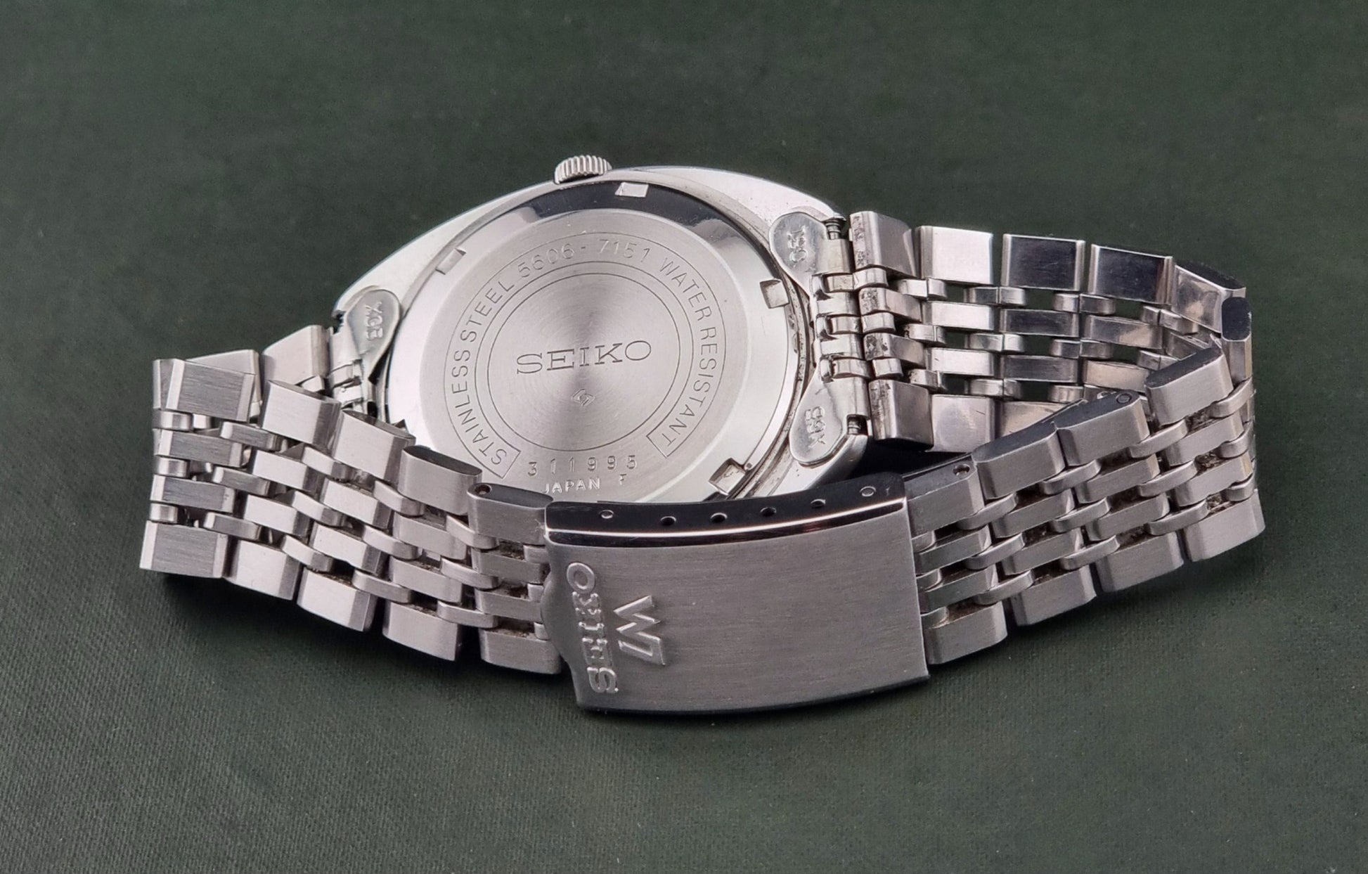 Silver Seiko watch on a dark green background