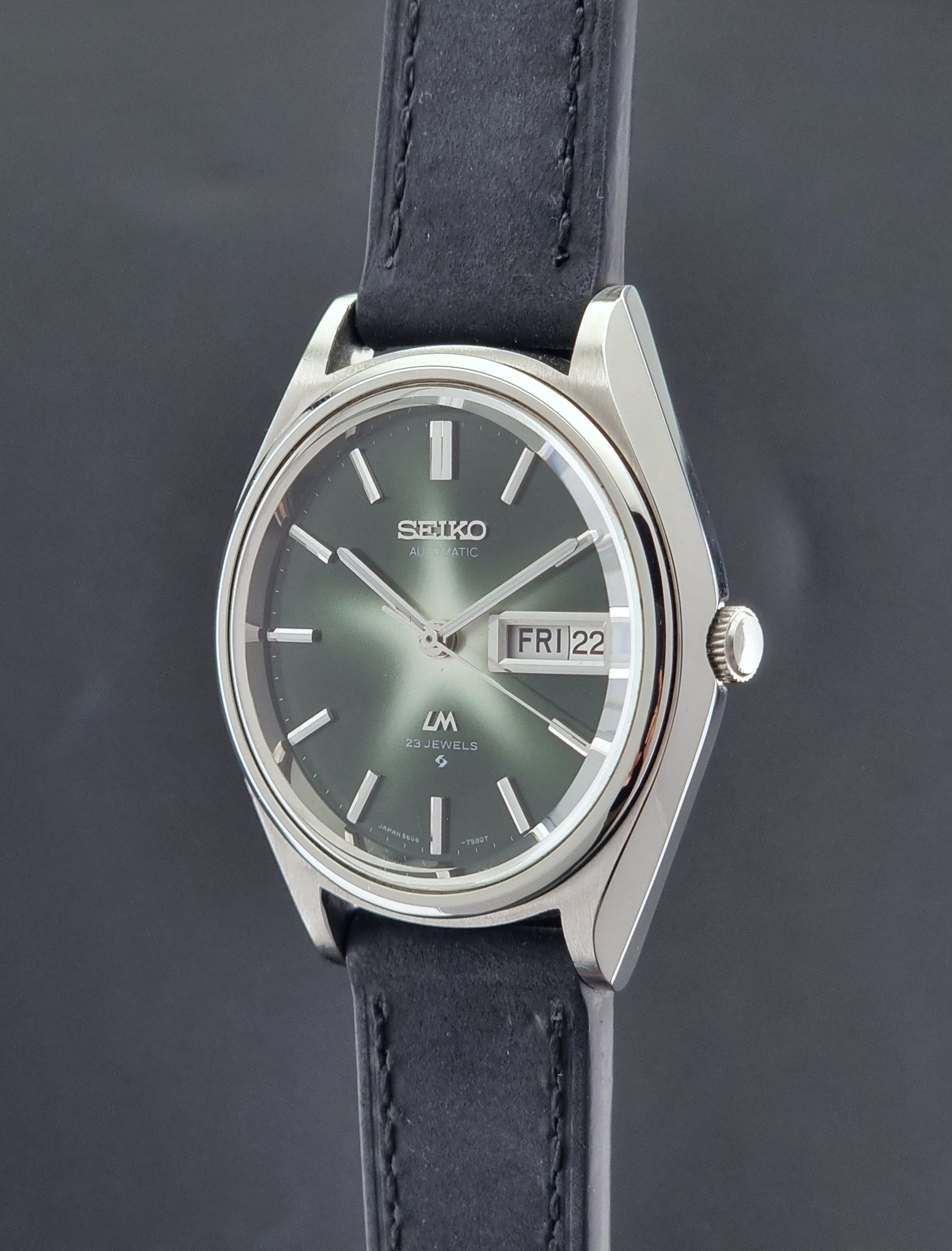 Seiko Lord Matic watch with a dark blue strap on a gray background